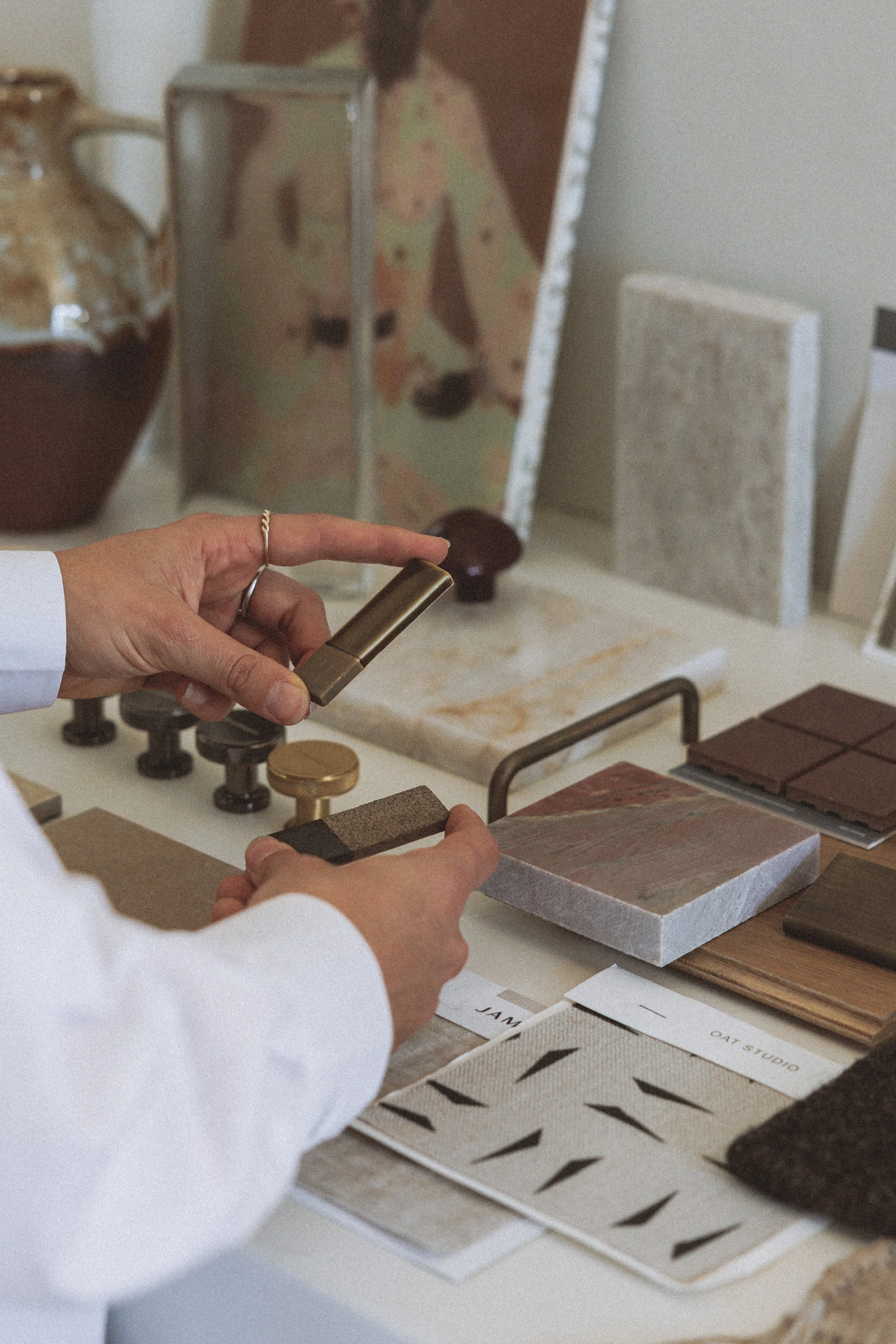 Person selecting material samples at a design studio with fabric, paint, and tile swatches.