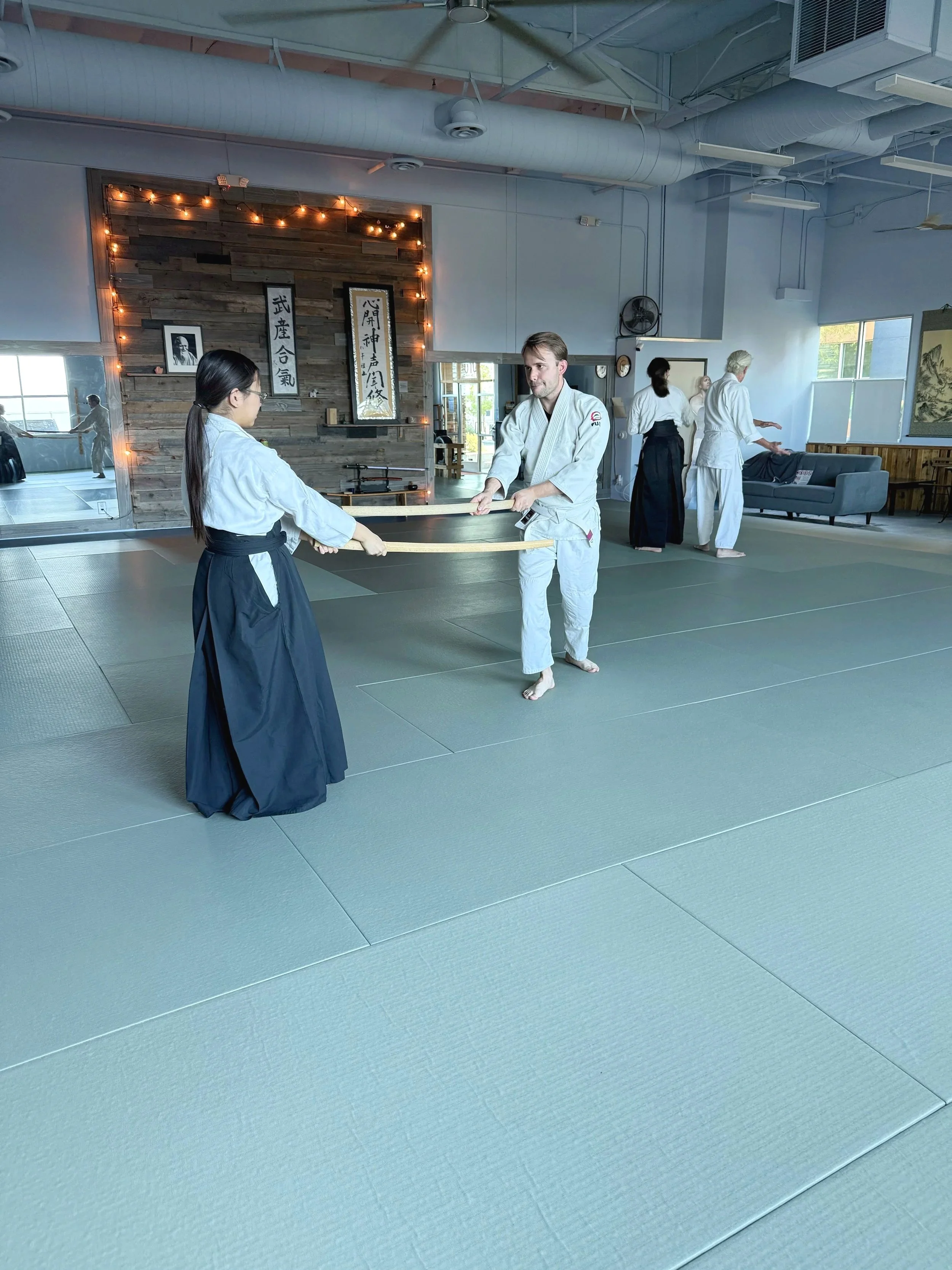 Aikido students practicing with bokken weapons at Henderson Aikido & Yoga