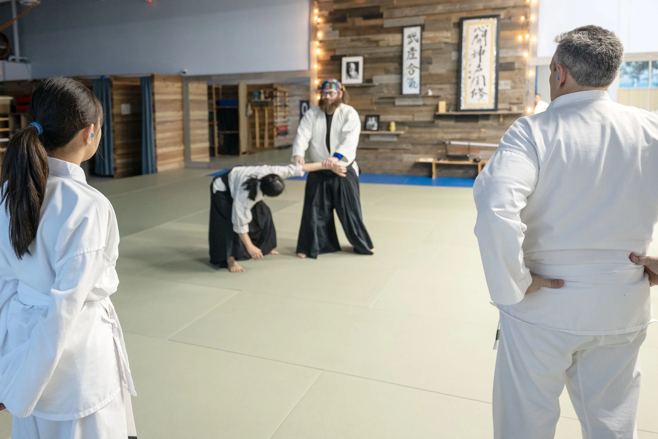 Two Aikido students watching their instructor demonstrate at Henderson Aikido & Yoga.