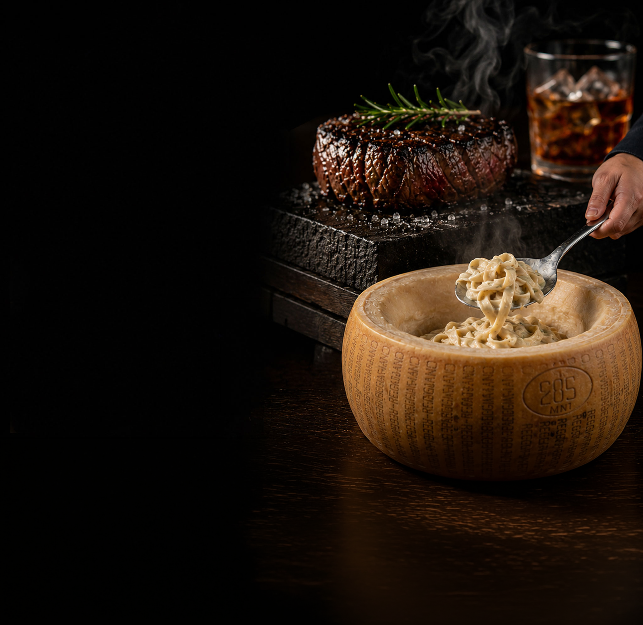 A sizzling steak cooked to medium rare with grill marks, garnished with a sprig of rosemary, served on a black stone slab with coarse salt. In the background, a glass of whiskey with ice and a hand holding a spoon.