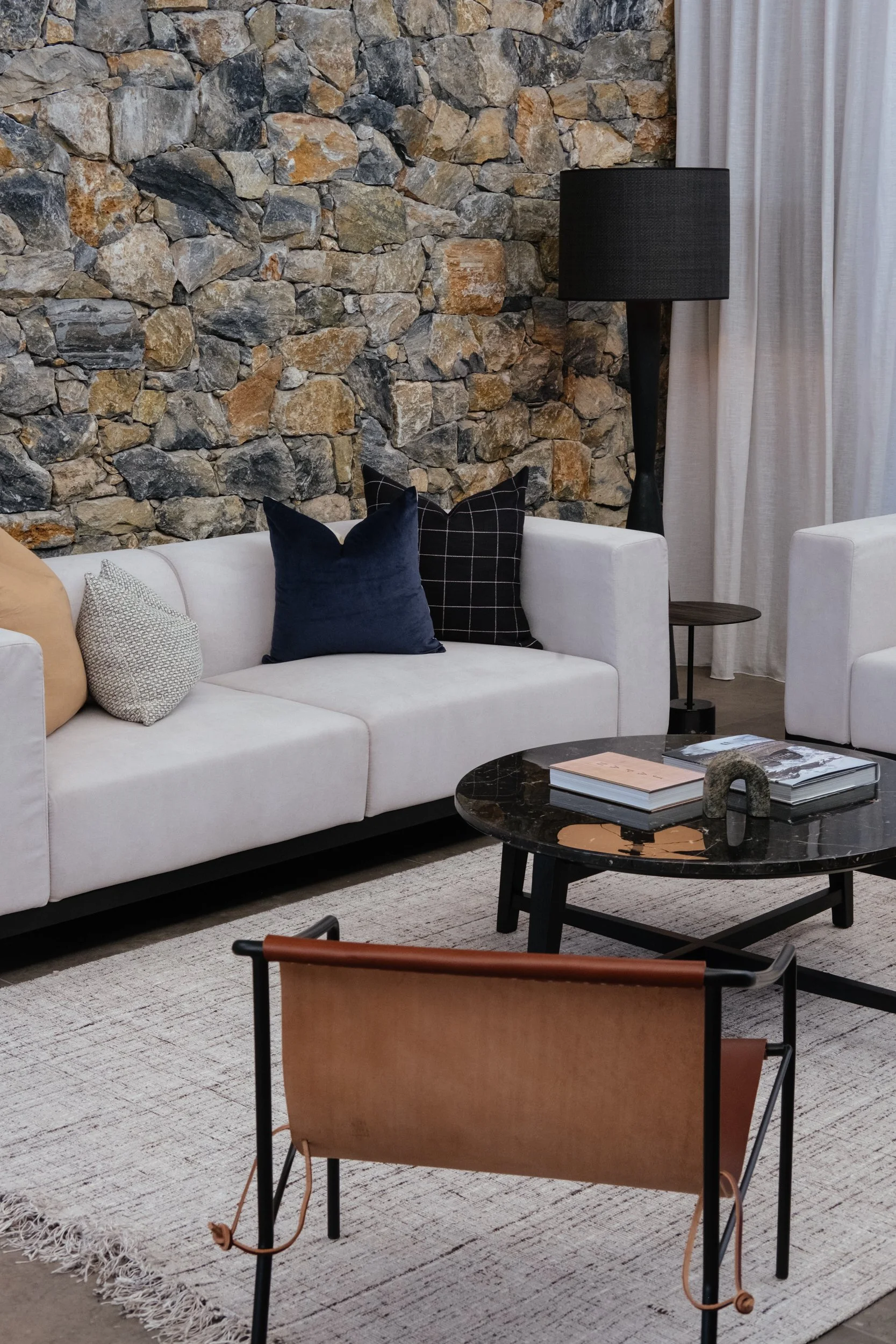Earthy living room styled beautifully with black lamp, silver grey sofas and tan leather chair.