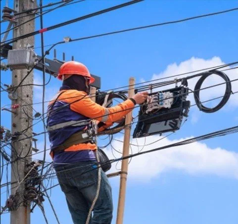 Aerial fiber optic technician performing strand placement on utility pole