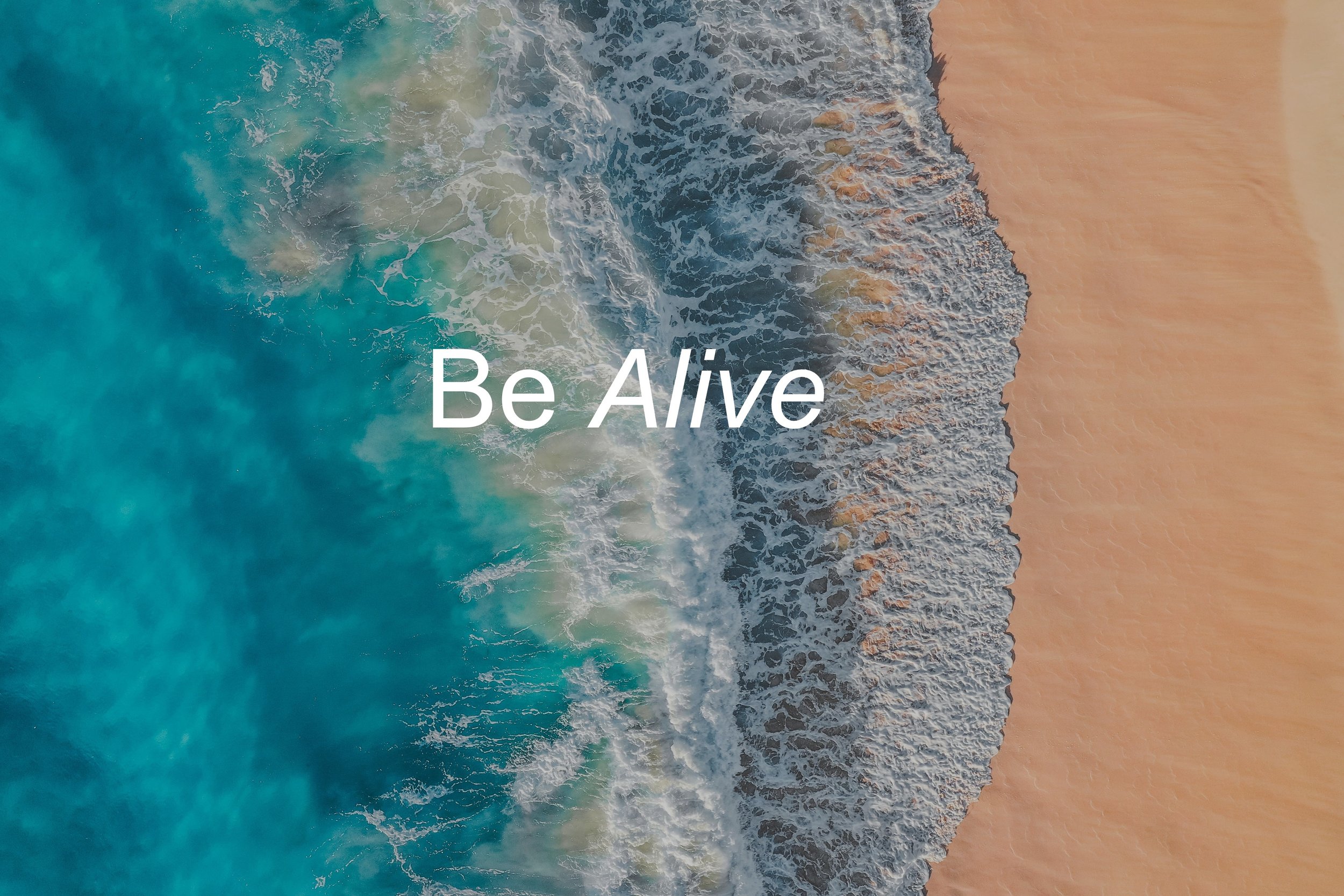 Aerial view of ocean waves crashing onto sandy beach with the message 'Be Alive' written across the image.
