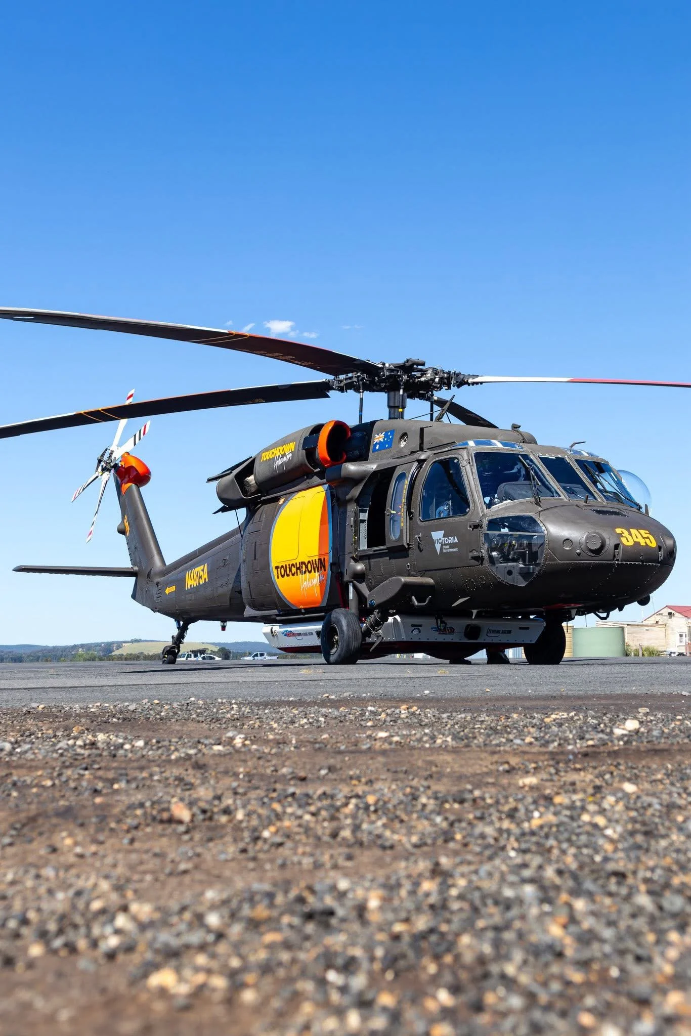 Military helicopter on tarmac with clear blue sky overhead.