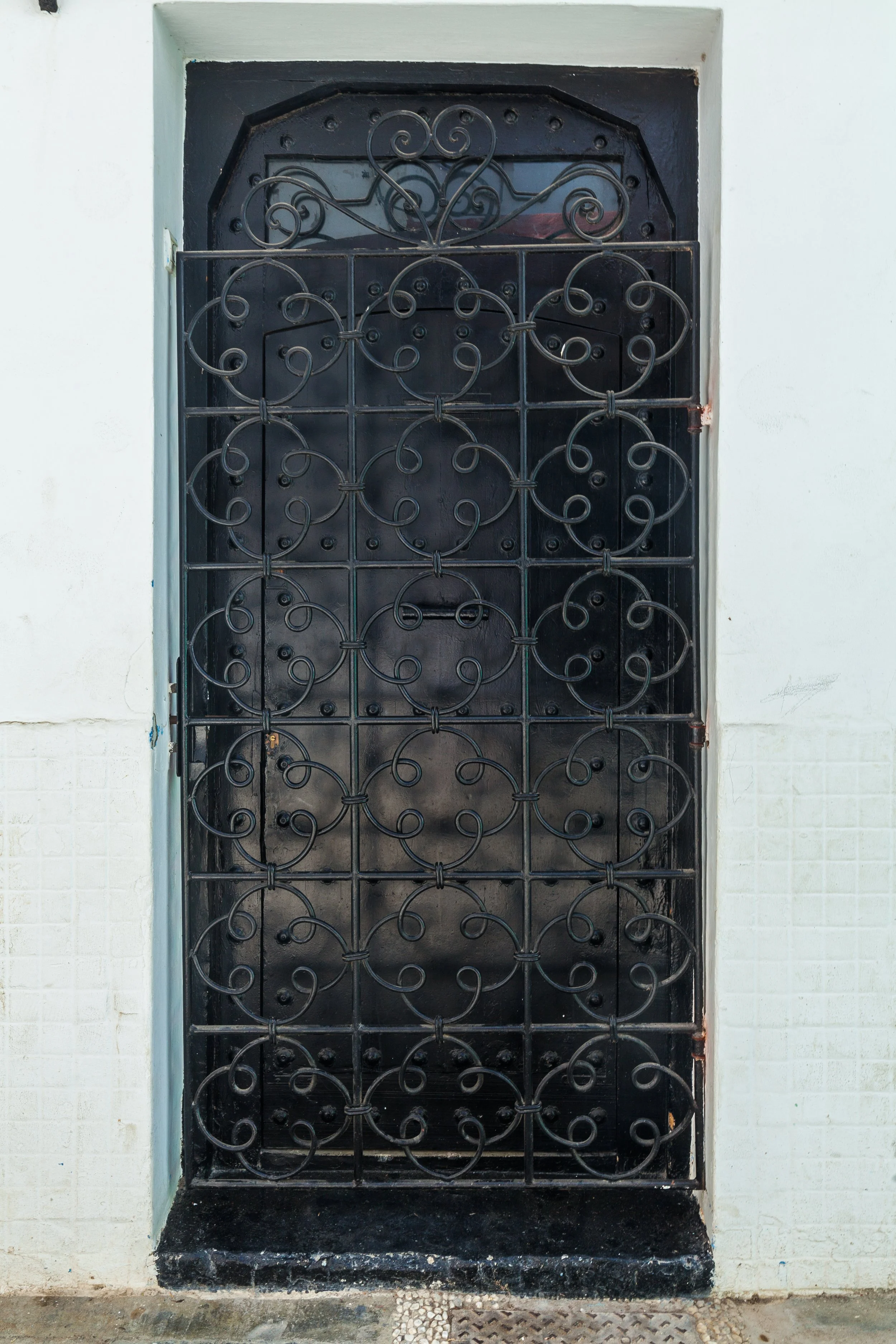 closeup-ornate-black-wrought-iron-gate-with-intricate-swirling-patterns-providing-glimpse-into-architectural-details-craftsmanship-traditional-building.jpg