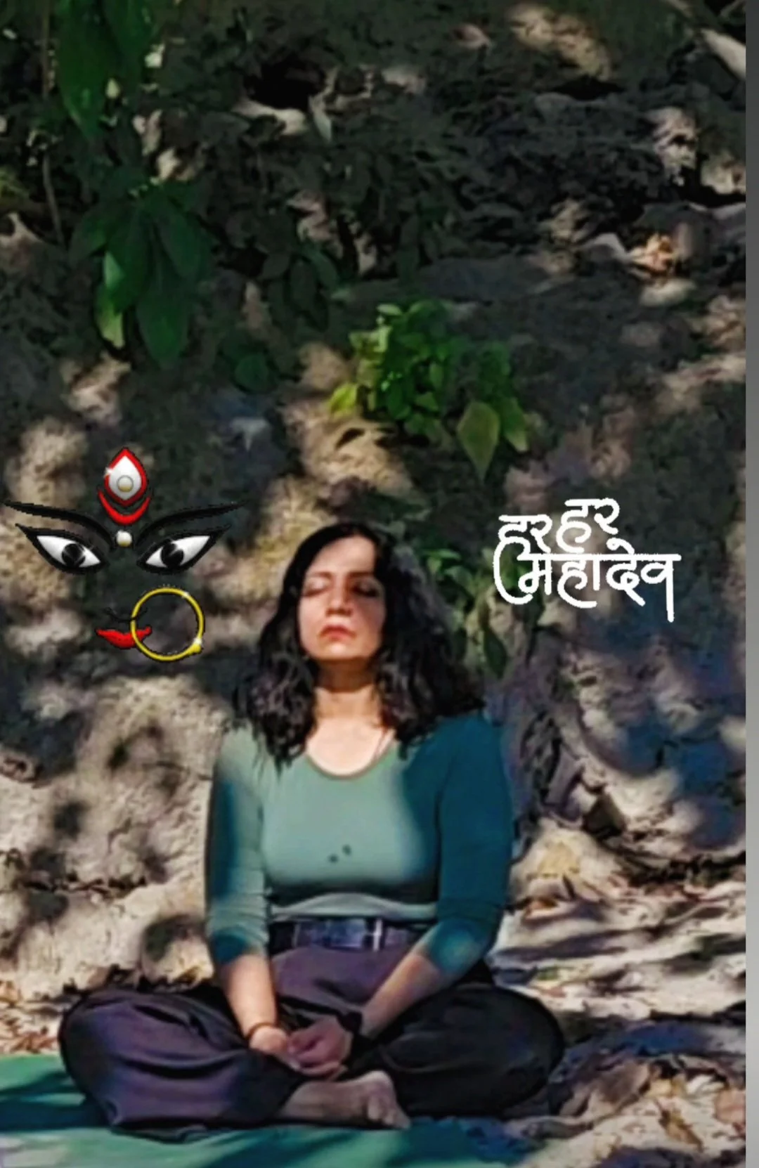 A woman sitting cross-legged outdoors on rocks with green foliage in the background, nighttime. Digital illustrations of a goddess face with eyes, a red and white headpiece, and a yellow nose ring are overlaid, along with Hindi text that reads "Shree Mahalaxmi".