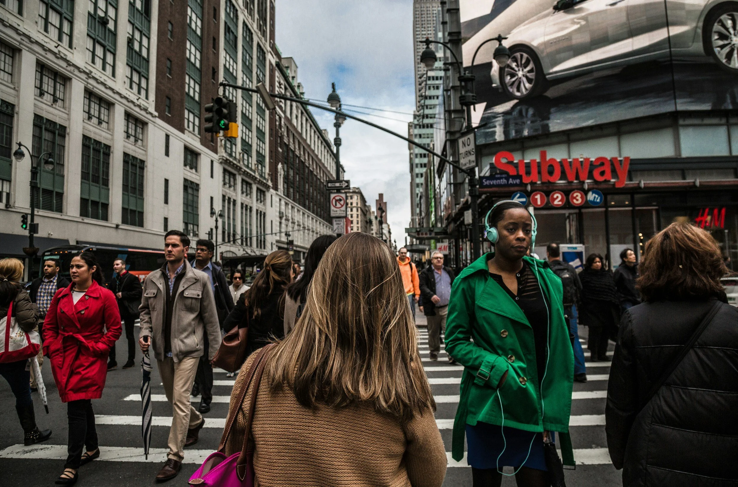 Busy city street crossing with crowds of people, representing the pace and demands of modern life