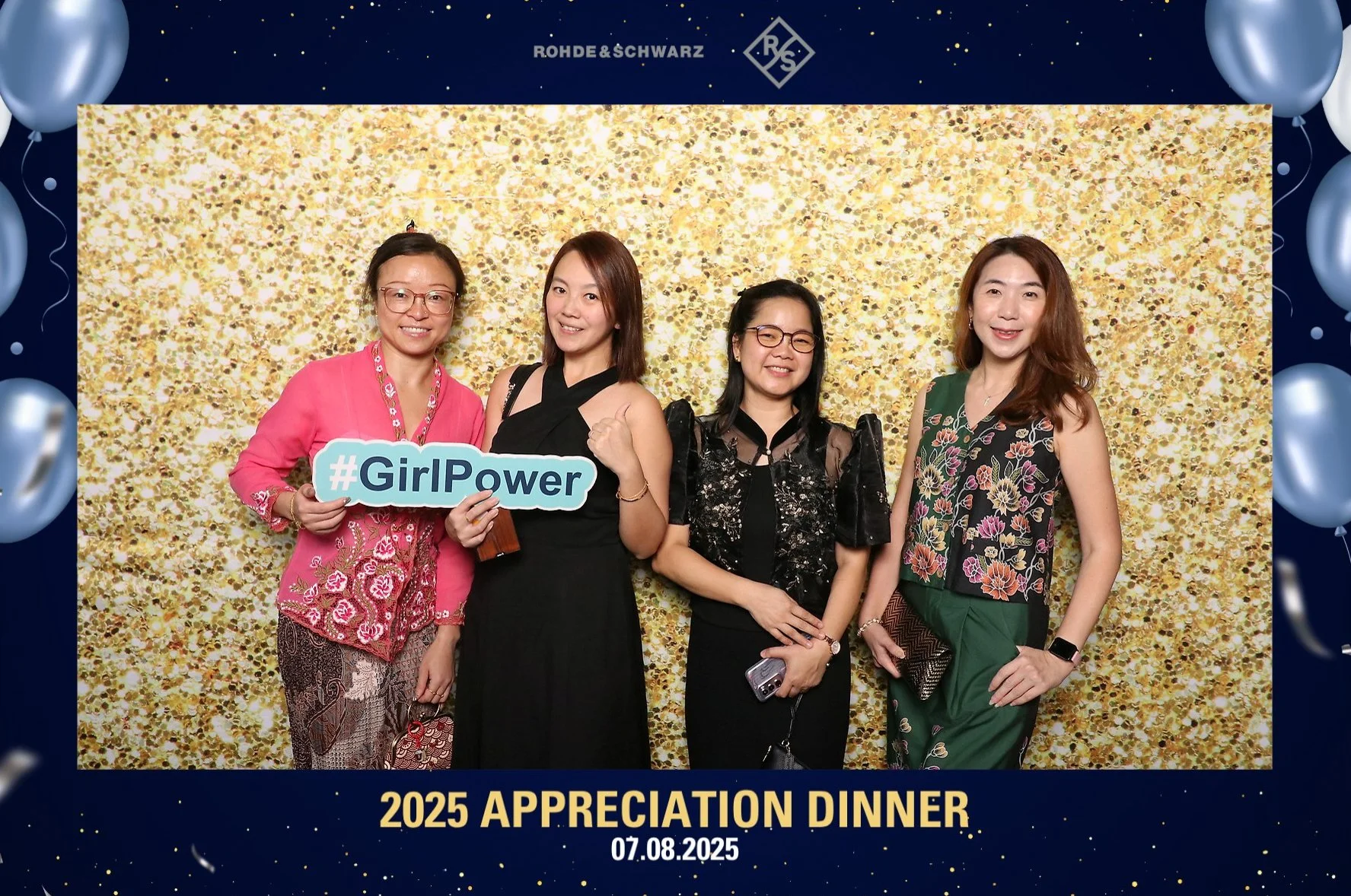 Four women standing together in front of a gold glitter backdrop at the 2025 Appreciation Dinner on July 8, 2025. One woman is holding a sign that says '#GirlPower,' and they are smiling for the camera.