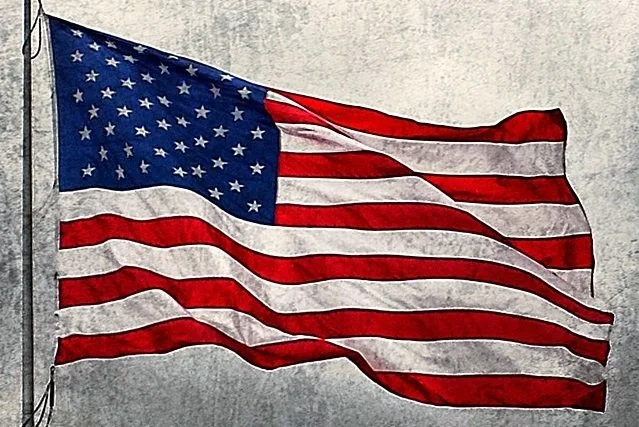 American flag waving against a cloudy sky background.