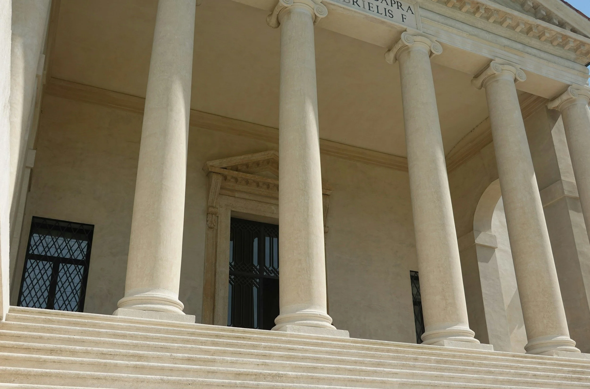 Dettaglio di una facciata di un edificio storico di Vicenza con colonne di stile classico, scale di pietra e finestre con infissi in ferro.