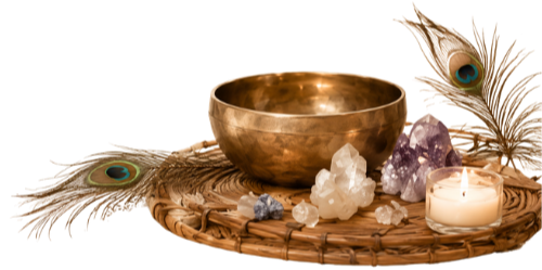 A singing bowl, various crystals, peacock feathers, and a lit candle on a woven mat.