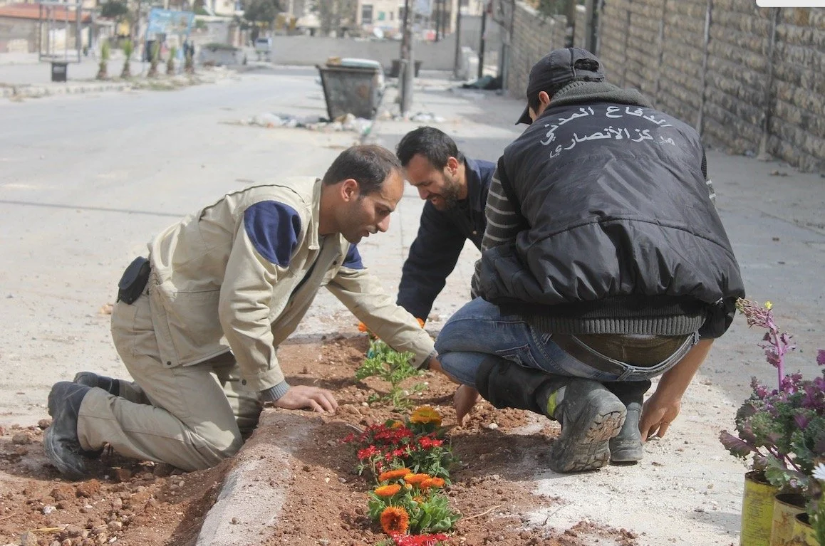 White Helmet Volunteers planting flowers in an effort to brighten the Syrian streets as part of their community engagement and outreach work.  Photograph reproduced with kind permission from the White Helmets.
