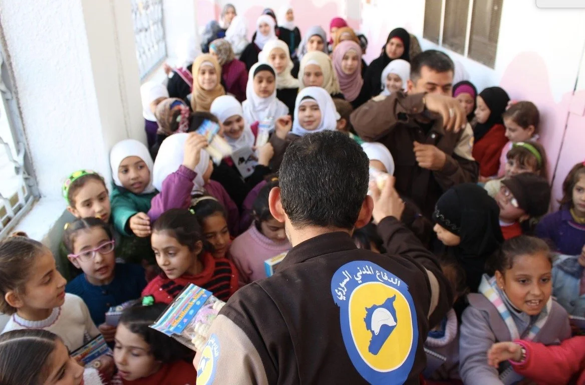 Members of the White Helmets delivering psychosocial support to children and young people in their local community affected by the ongoing conflict.  Photograph reproduced with kind permission from the White Helmets.