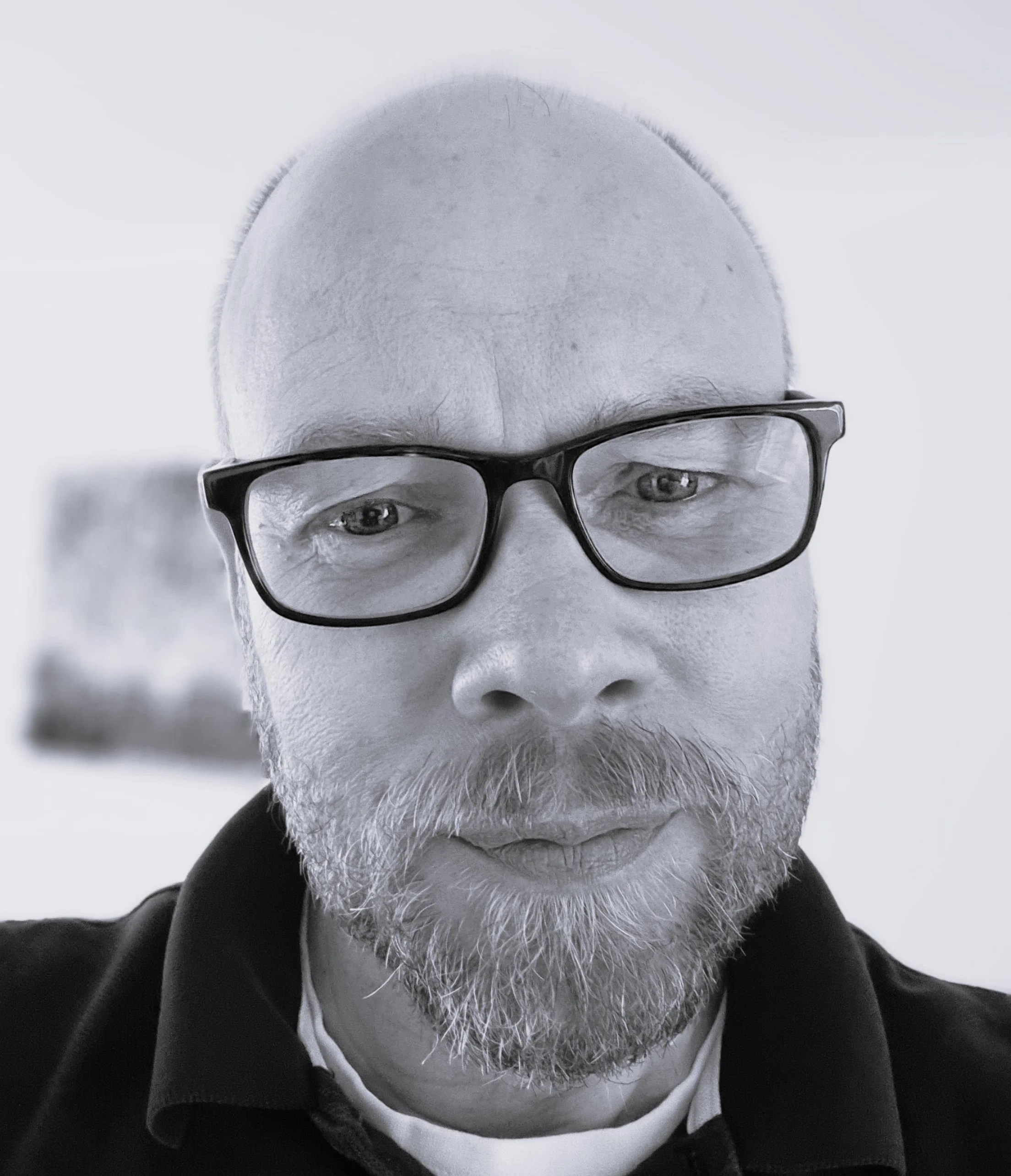 Close-up of a man with glasses, bald head, and a white beard looking directly at the camera.