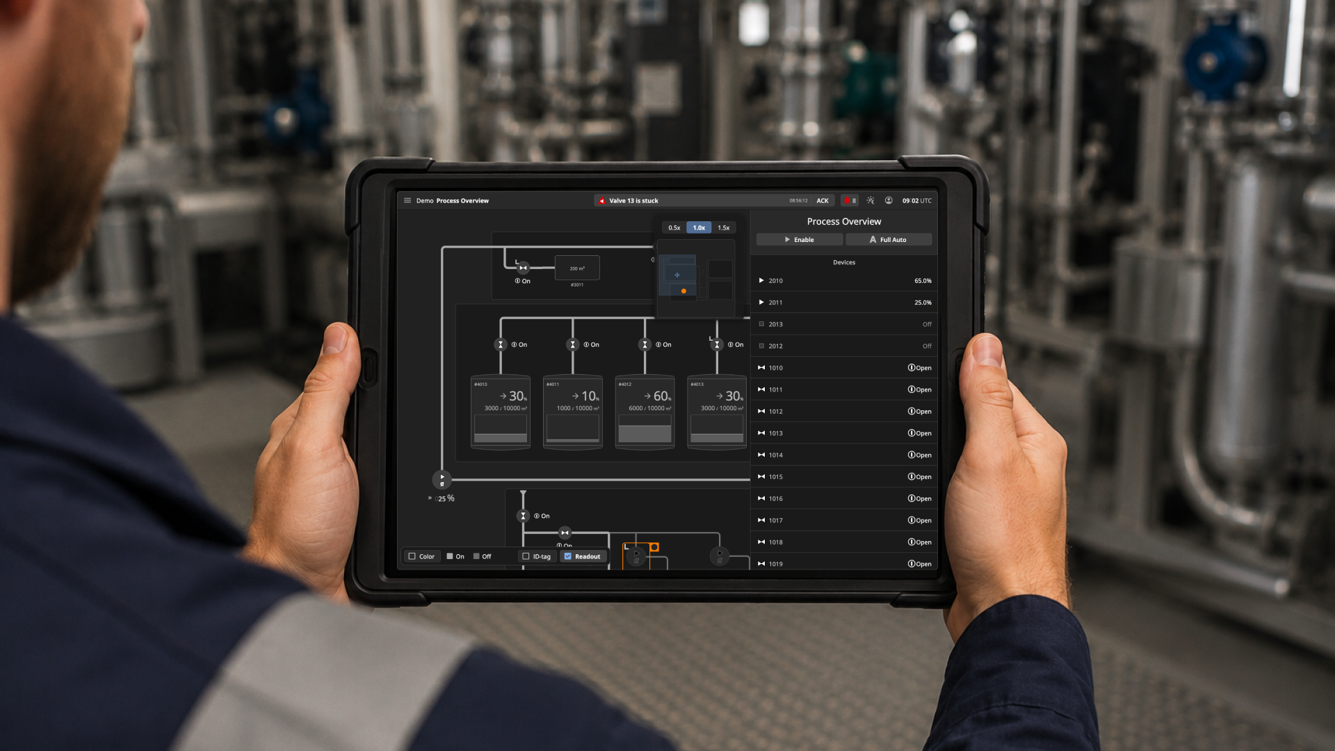 Person holding a tablet displaying a process control diagram in an industrial setting.