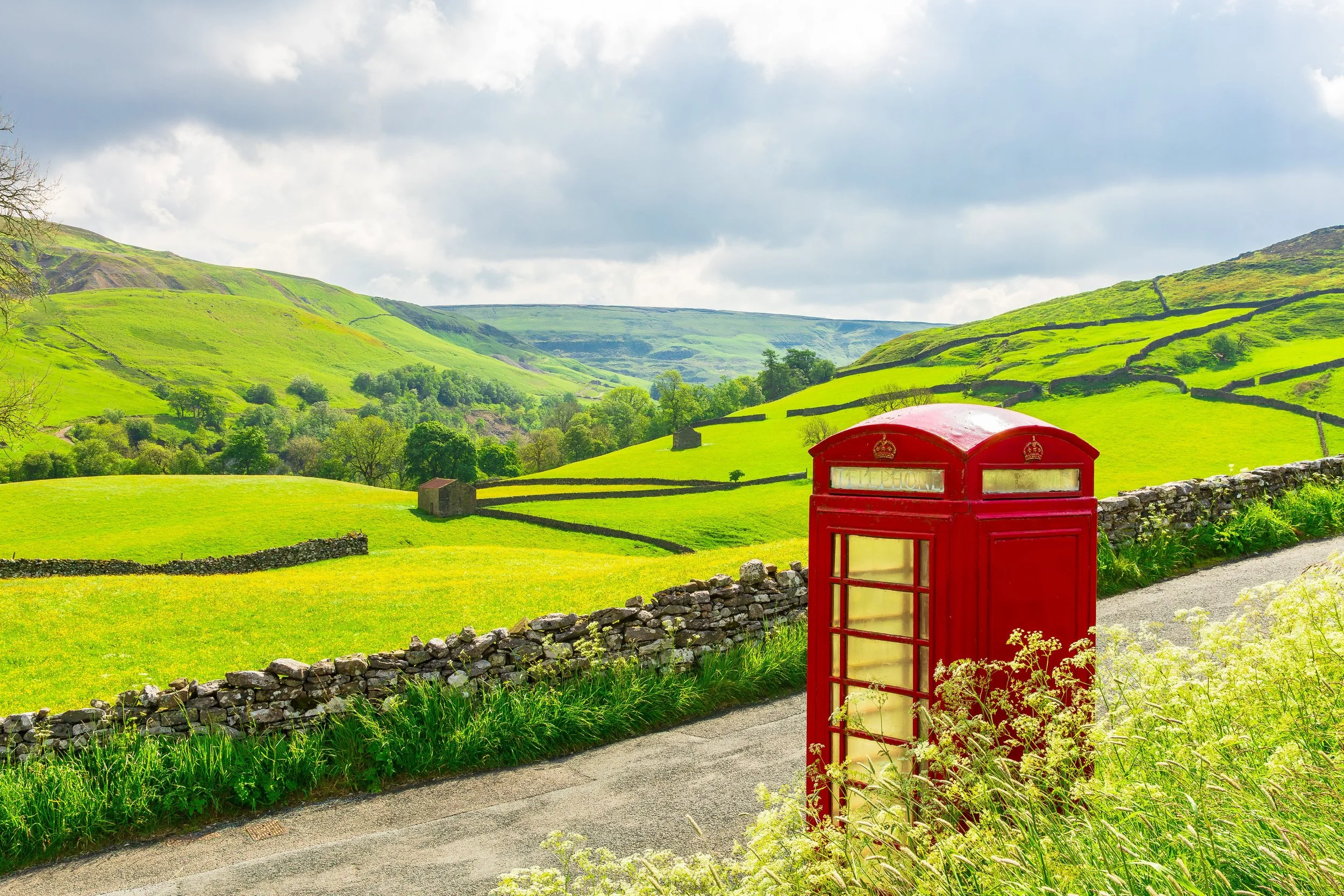 Red telephone box beside a country road in a North Yorkshire rural landscape.