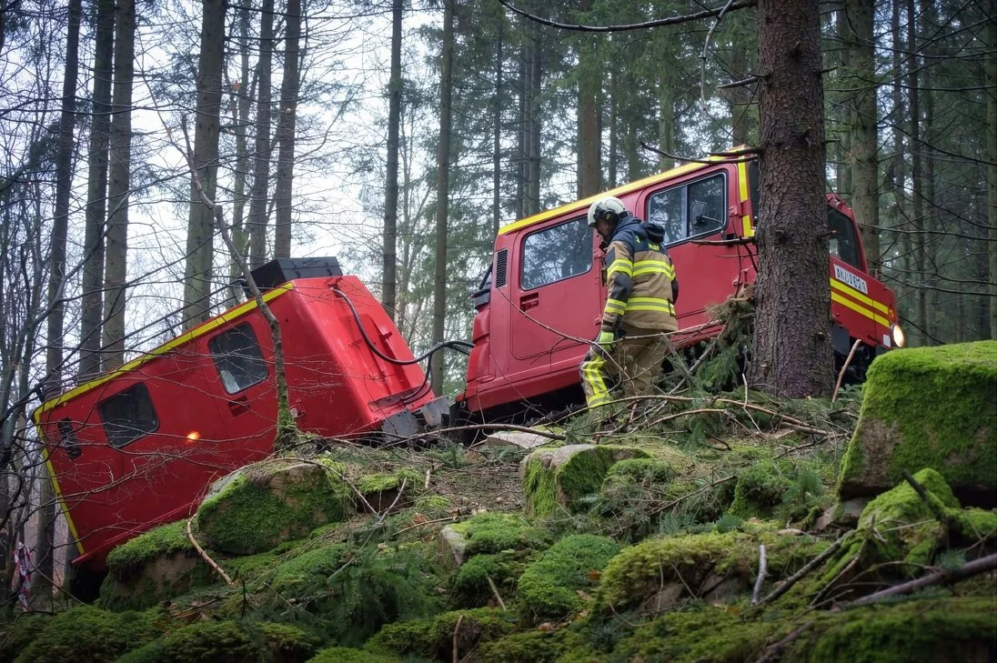 Brandbil har kört av vägen i en skog och är kapad i delar, en brandman undersöker platsen.