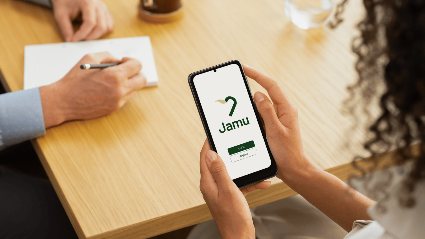 Woman holds a phone in her hand that shows the Login page of the the Jamu Application
