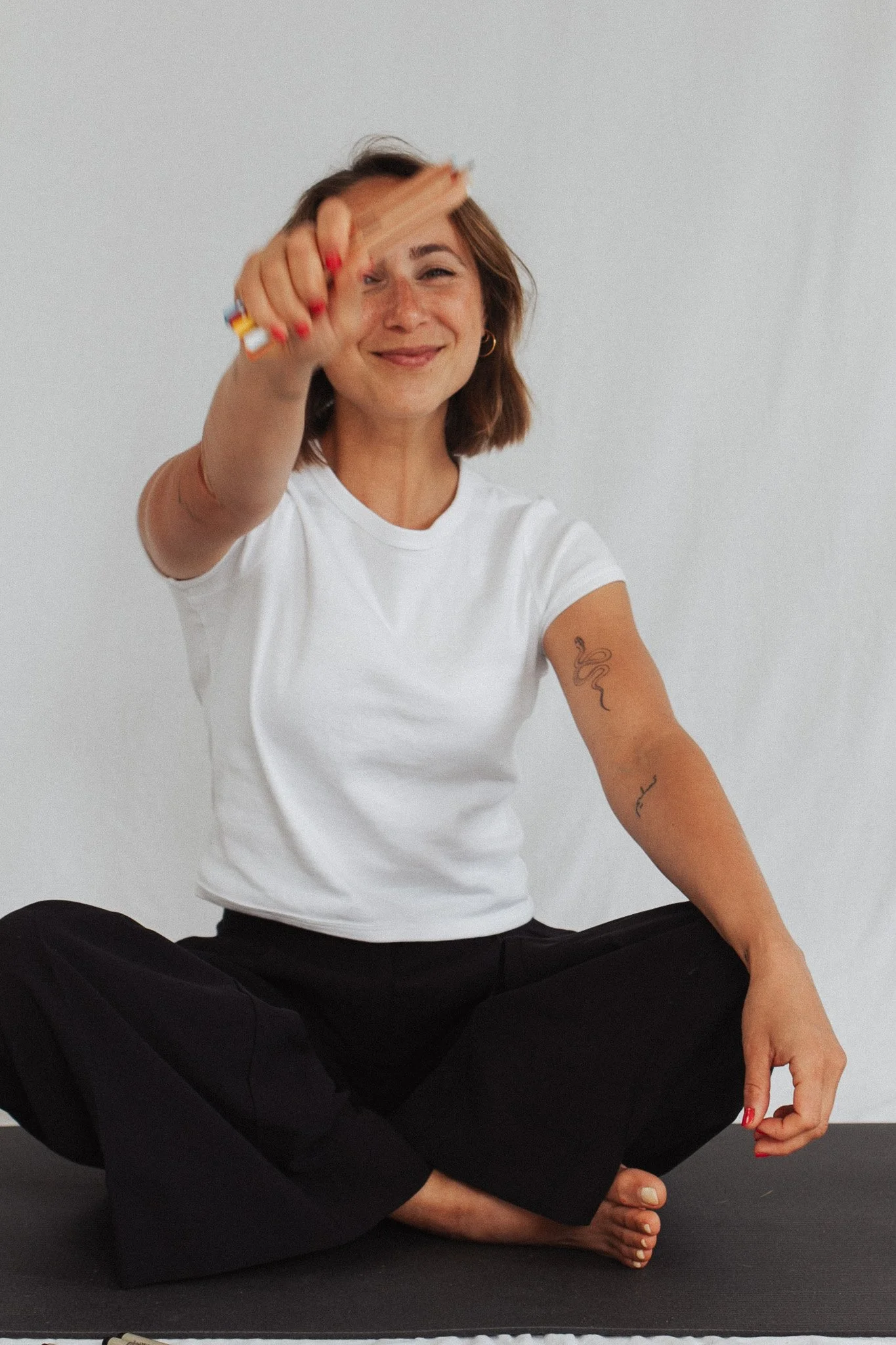 A playful picture of Liana with colored pencils in her hands, holding towards the camera and smiling joyfully.