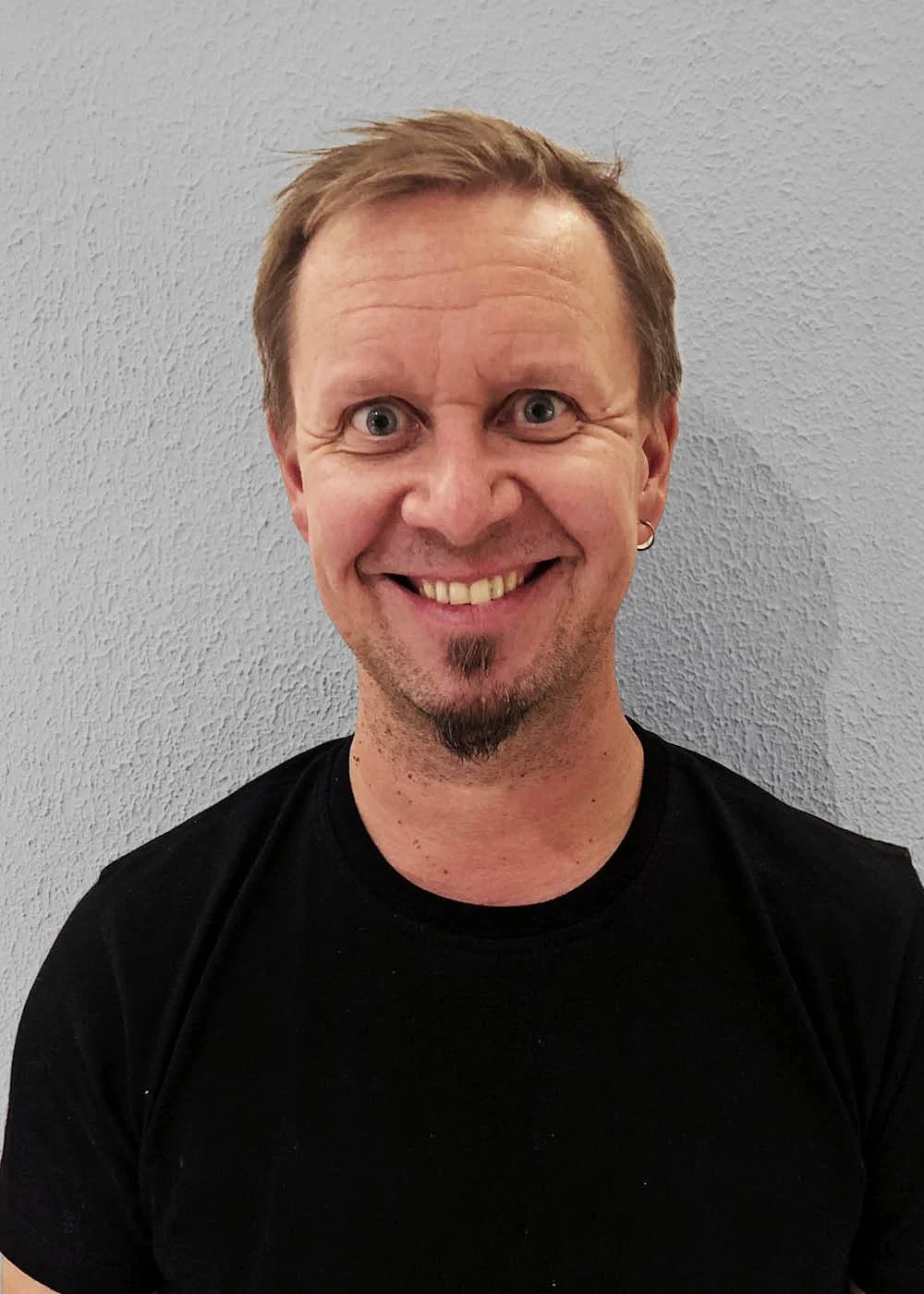 Henkilö hymyilee ja katsoo kameraan.