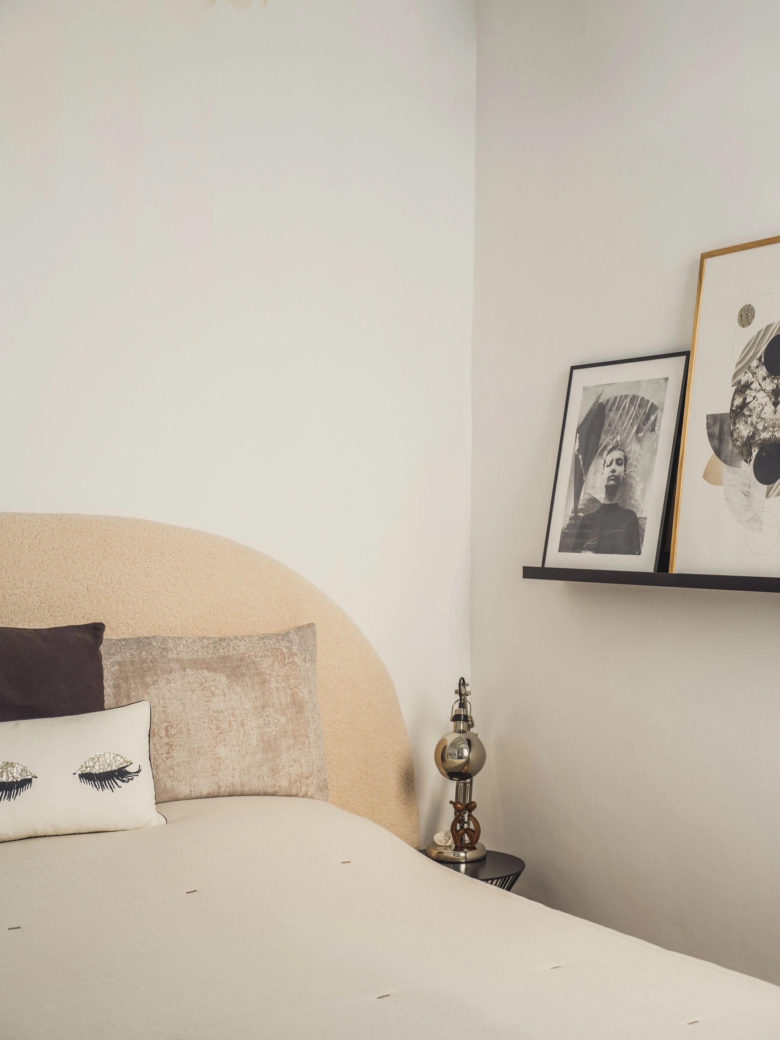 A bedroom corner with a bed, decorative pillows, and framed artwork on a wall.