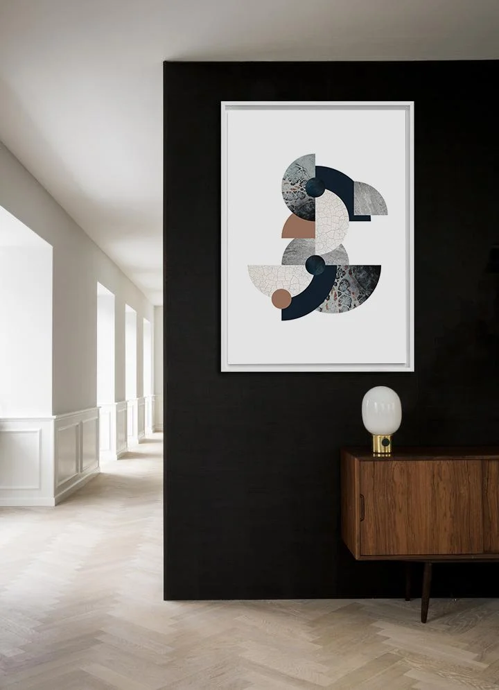 Modern interior hallway with abstract art on a black wall, wooden side table, and white lamp.