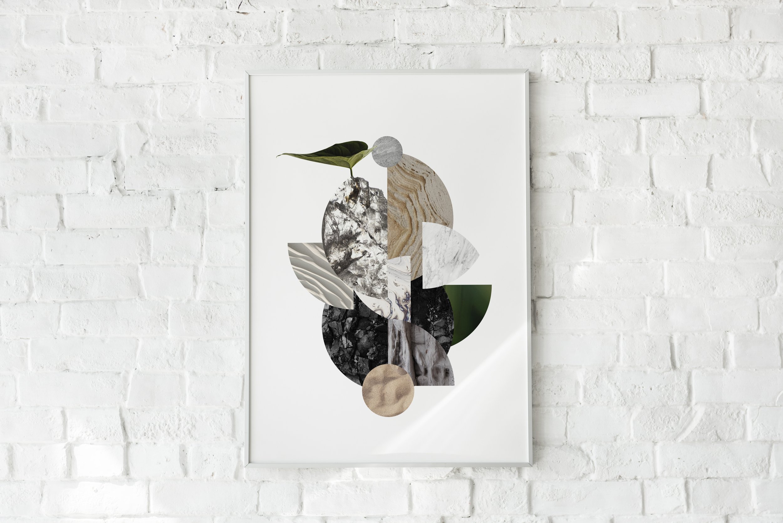 Abstract art print featuring various textured shapes and a green leaf on white background, hung on a white brick wall.