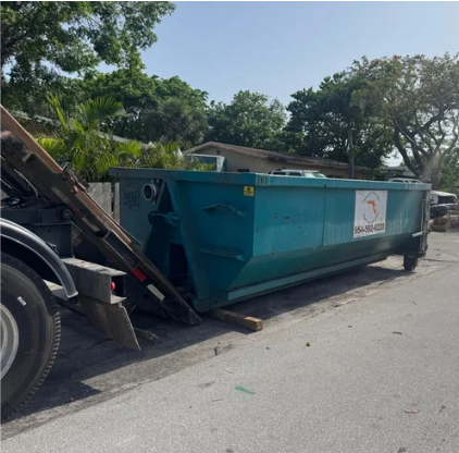 Large blue industrial dumpster on the side of the road, partially lifted by a truck.