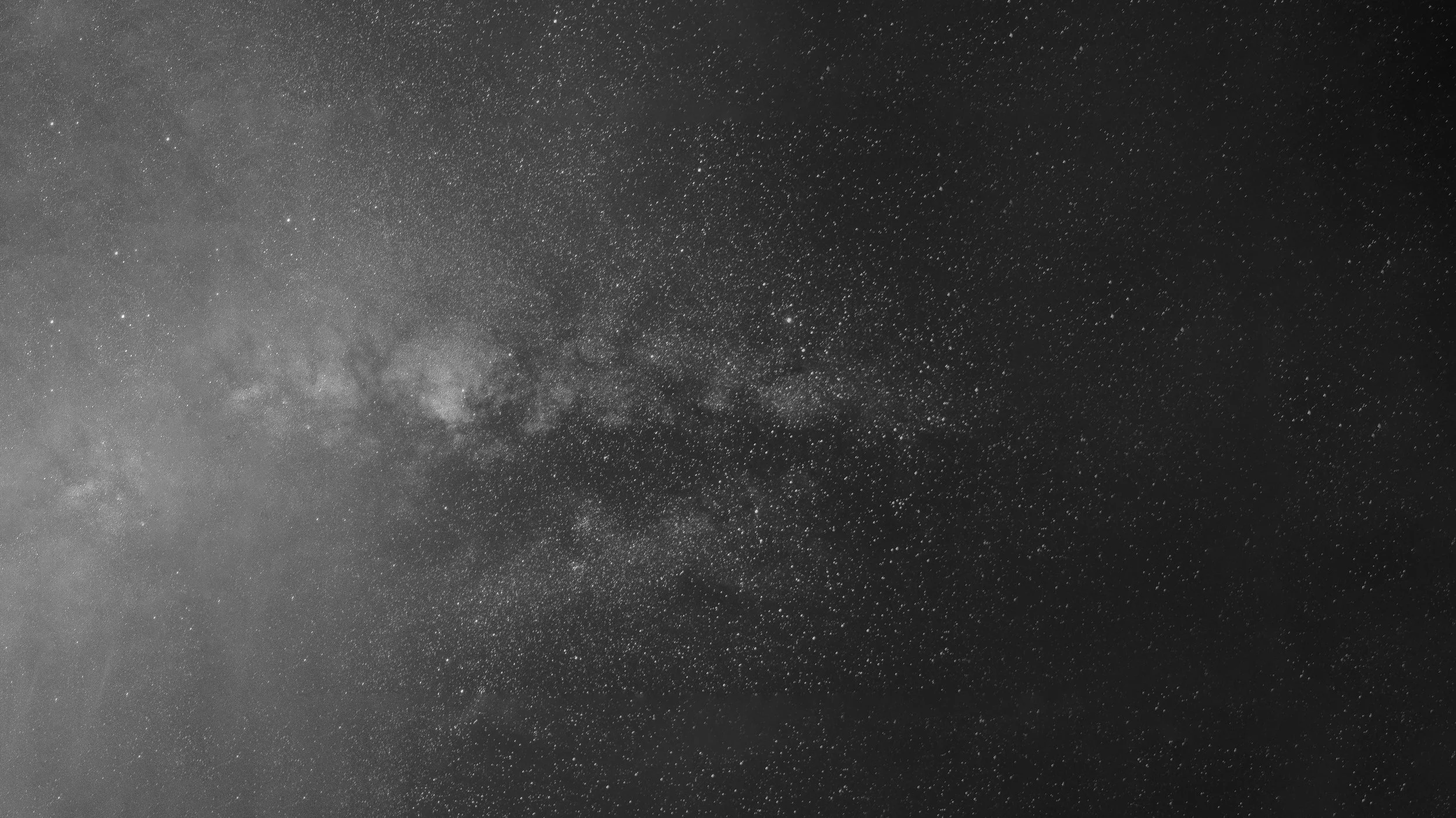 Black and white photograph of a starry night sky with numerous stars and the Milky Way galaxy visible.