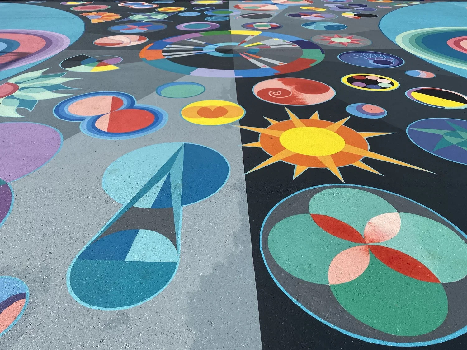 Colorful abstract geometric patterns on a flat surface, divided into two halves with different background colors, featuring circles, arrows, and star shapes.