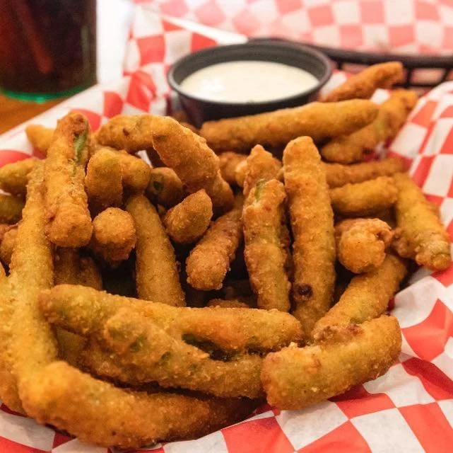 Basket of fried green beans served with a side of ranch dressing.
