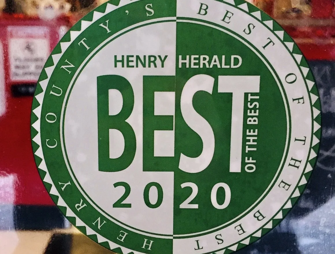 A circular sticker with green and white colors. The text reads, 'Henry Herald Best of the Best 2020.' The words are arranged around the circle, which has a zigzag border, and the center features large green and white text.