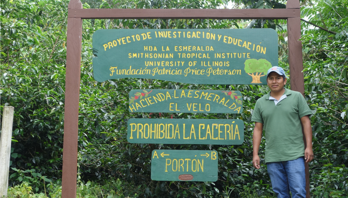 Fernando Callo, Hacienda La Esmeralda s field technician, stands in front of a sign welcoming visitors to the farm (photo: Stephanie Alcala).