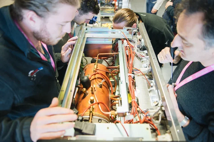People inspecting the inside of an espresso machine