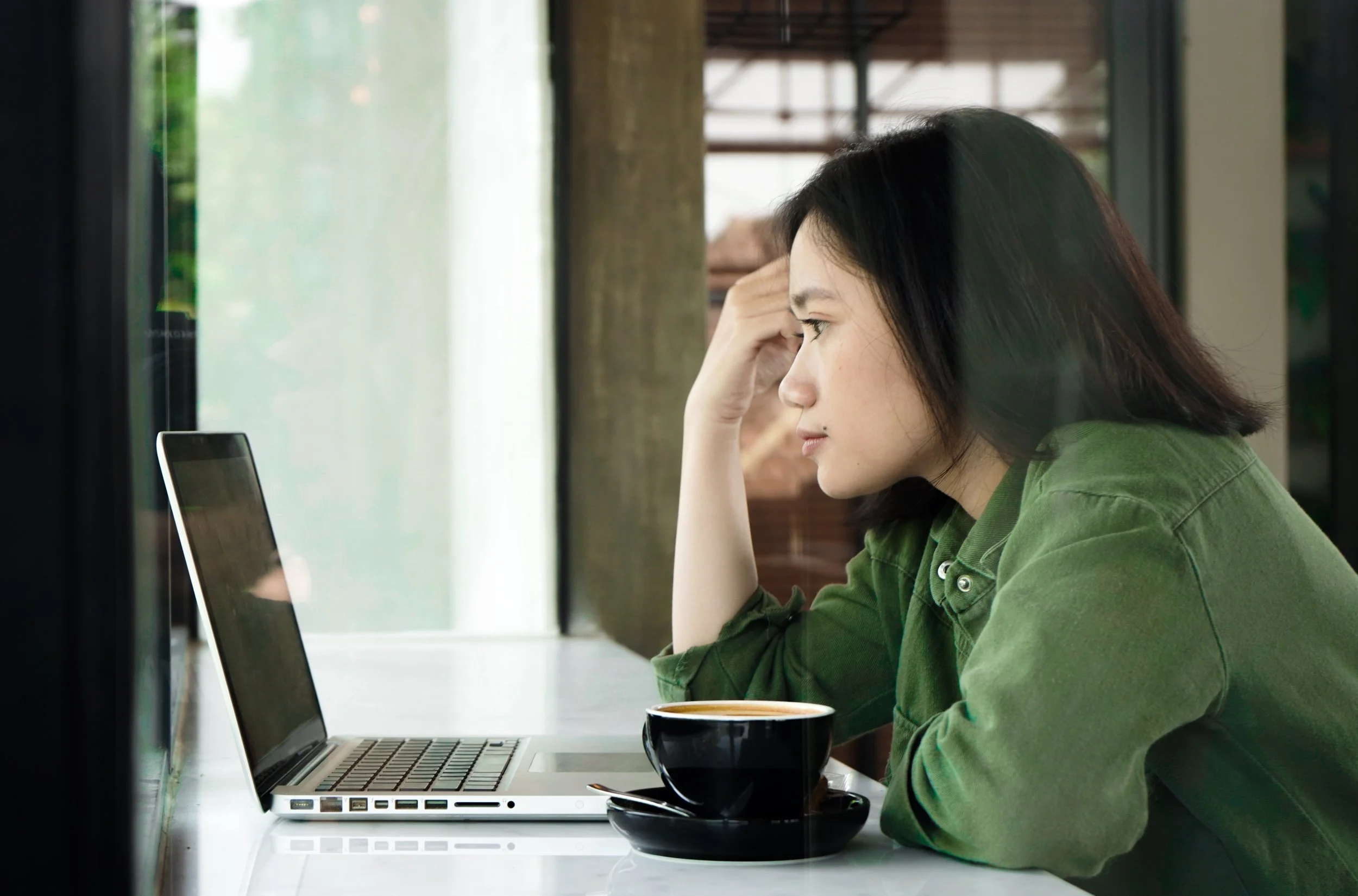 A person sitting at a counter looking at a laptop screen
