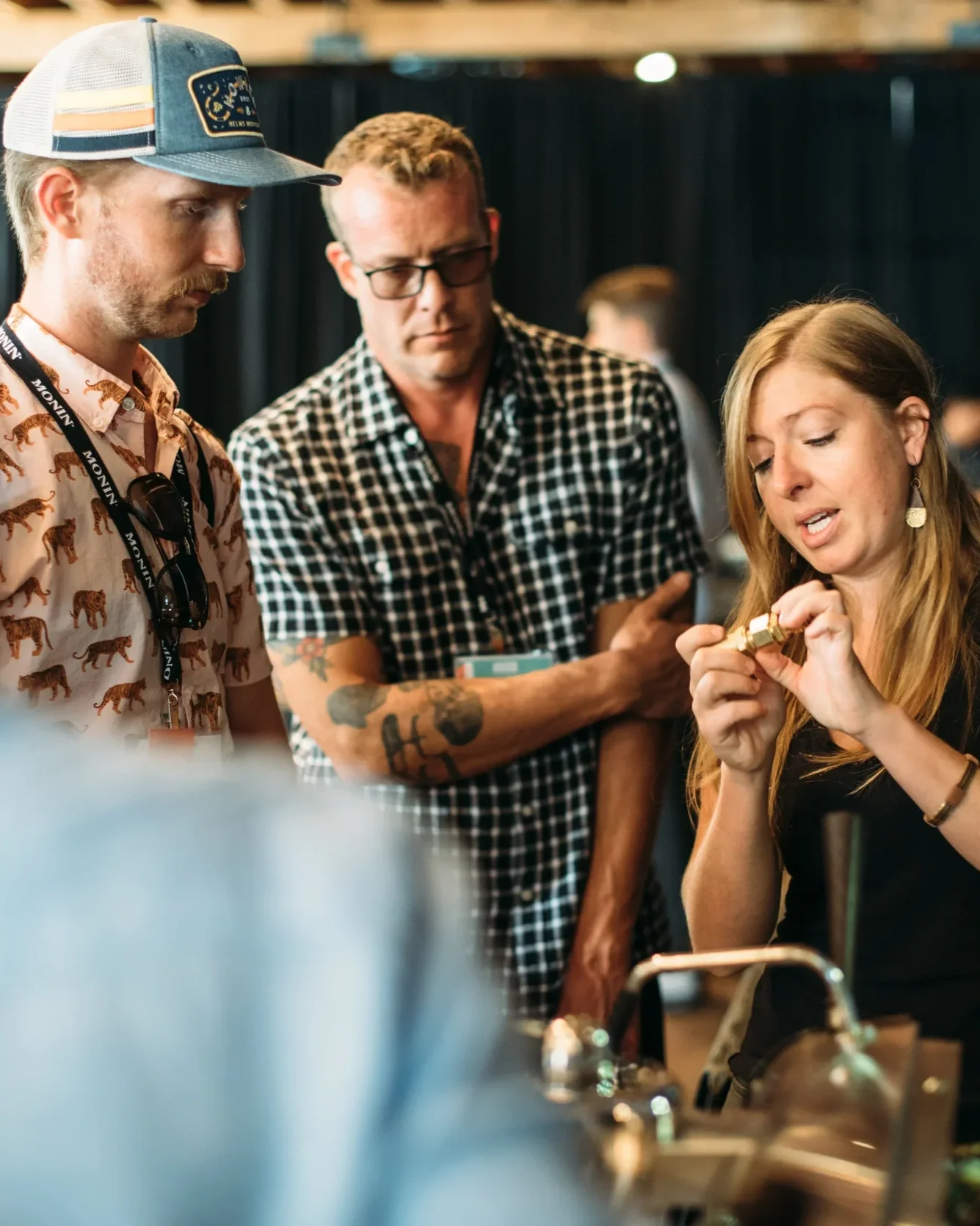 A trainer showing two learners a solenoid valve from an espresso machine.