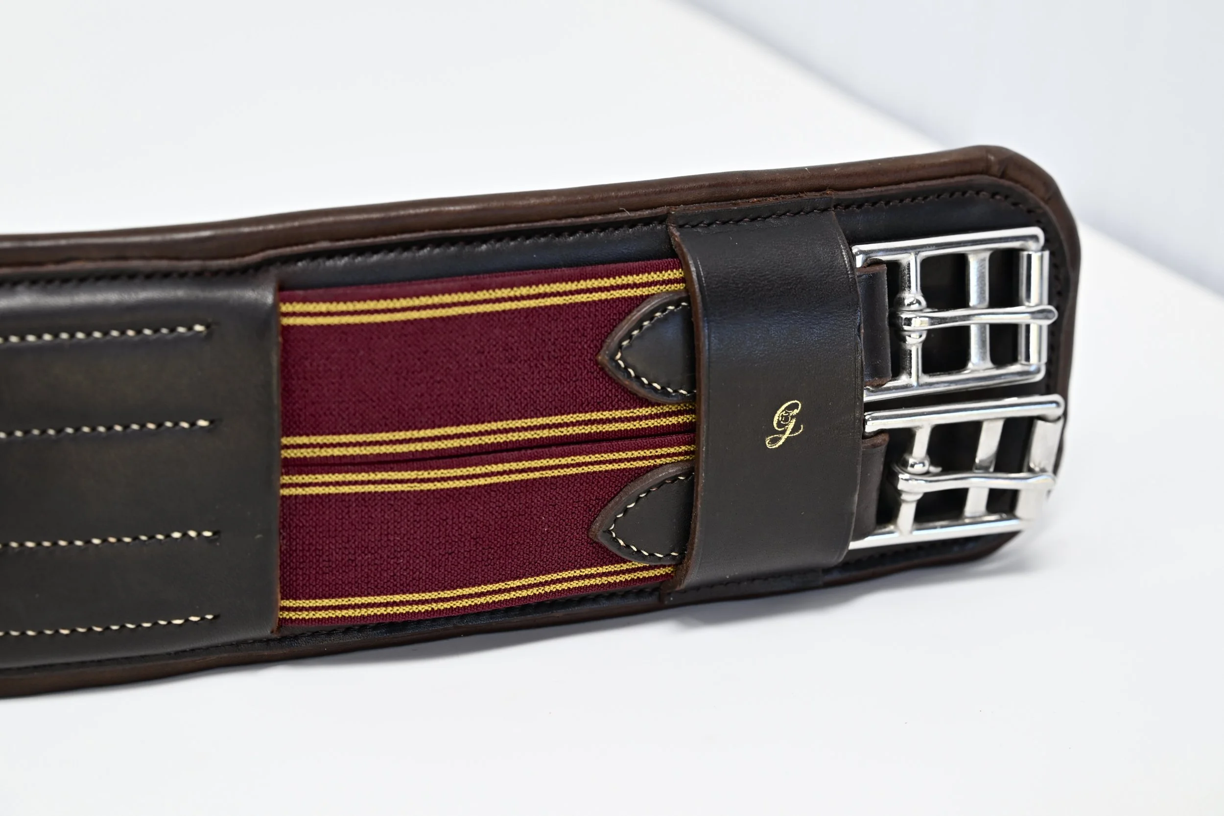 Ceinture en cuir avec un détail en tissu rouge et jaune, boucle métallique argentée.