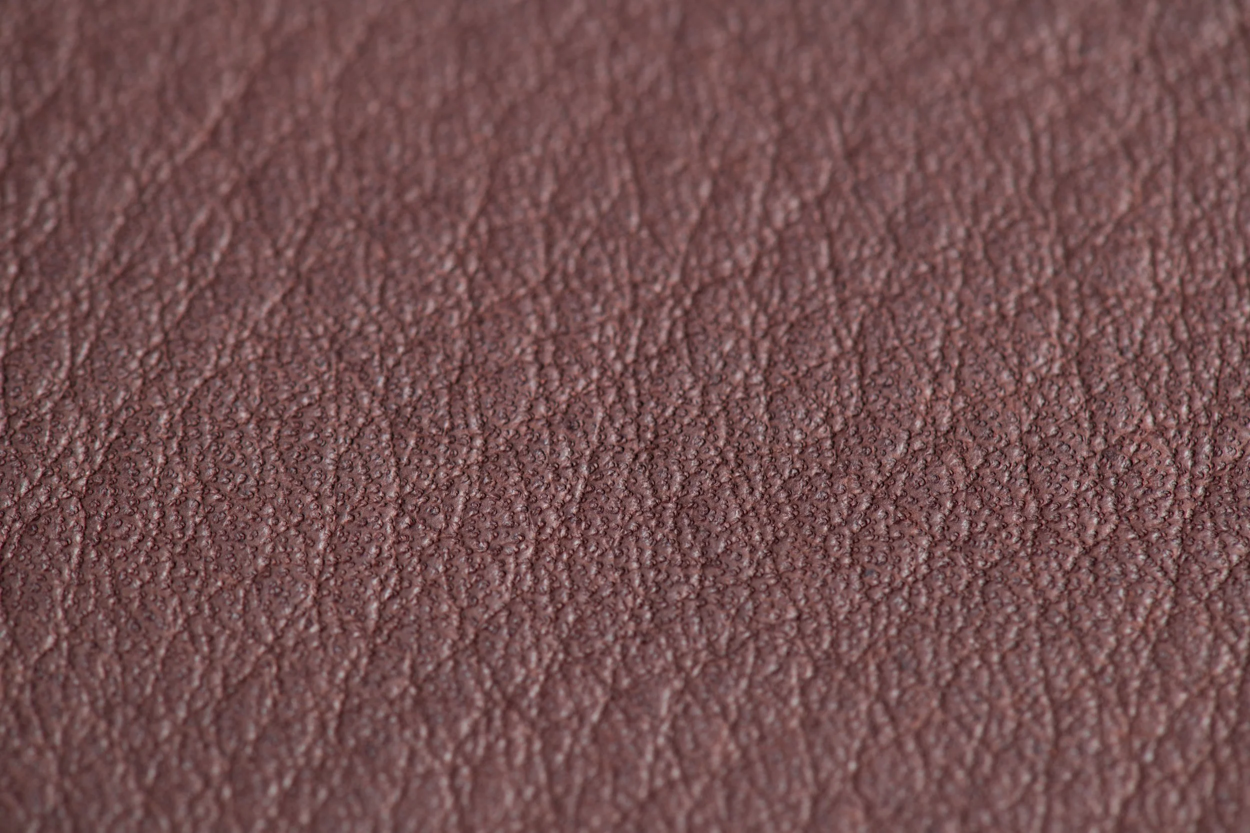 Zoom de près sur une texture en cuir de couleur marron avec un grain fin.