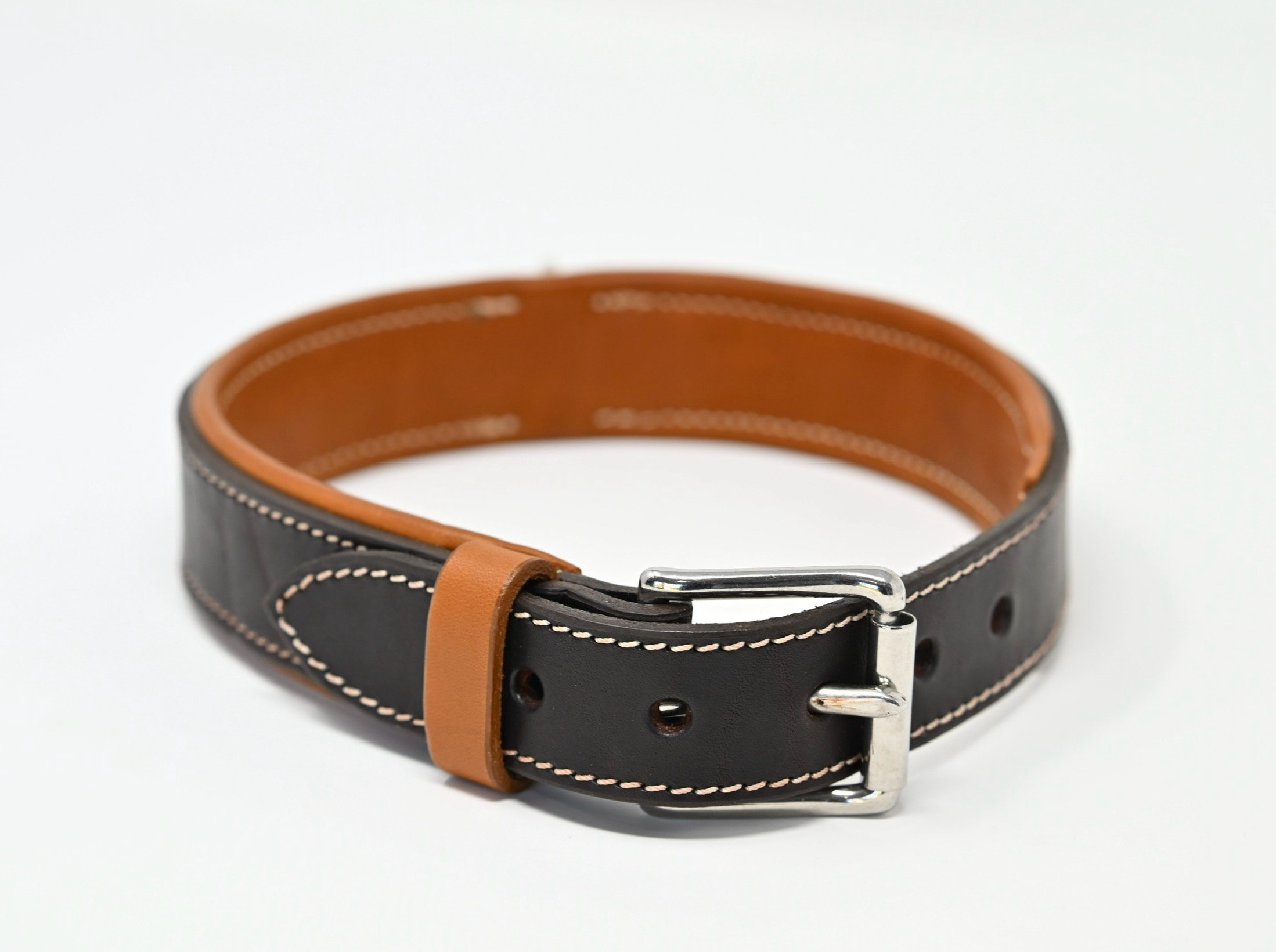 Ceinture en cuir noir avec doublure marron et boucle métallique.