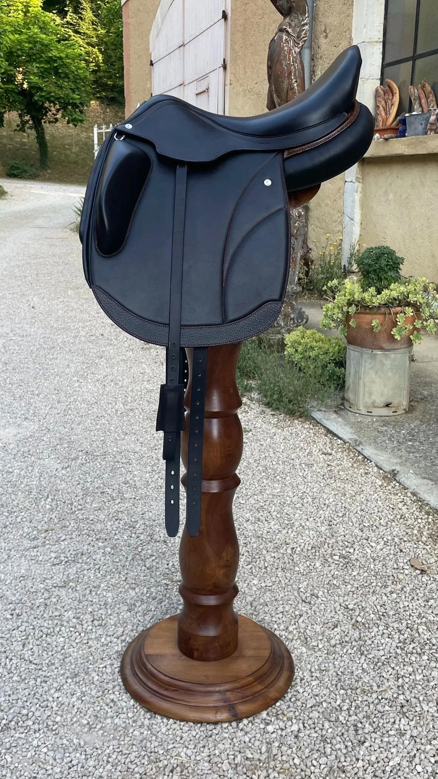 Un sac de selle noir posé sur un support en bois dans un environnement extérieur