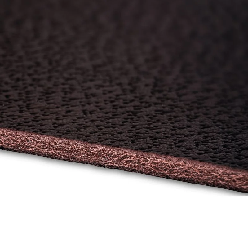 Détail d'une surface en matériau noir avec une texture légèrement rugueuse et un bord rose ou bronze.
