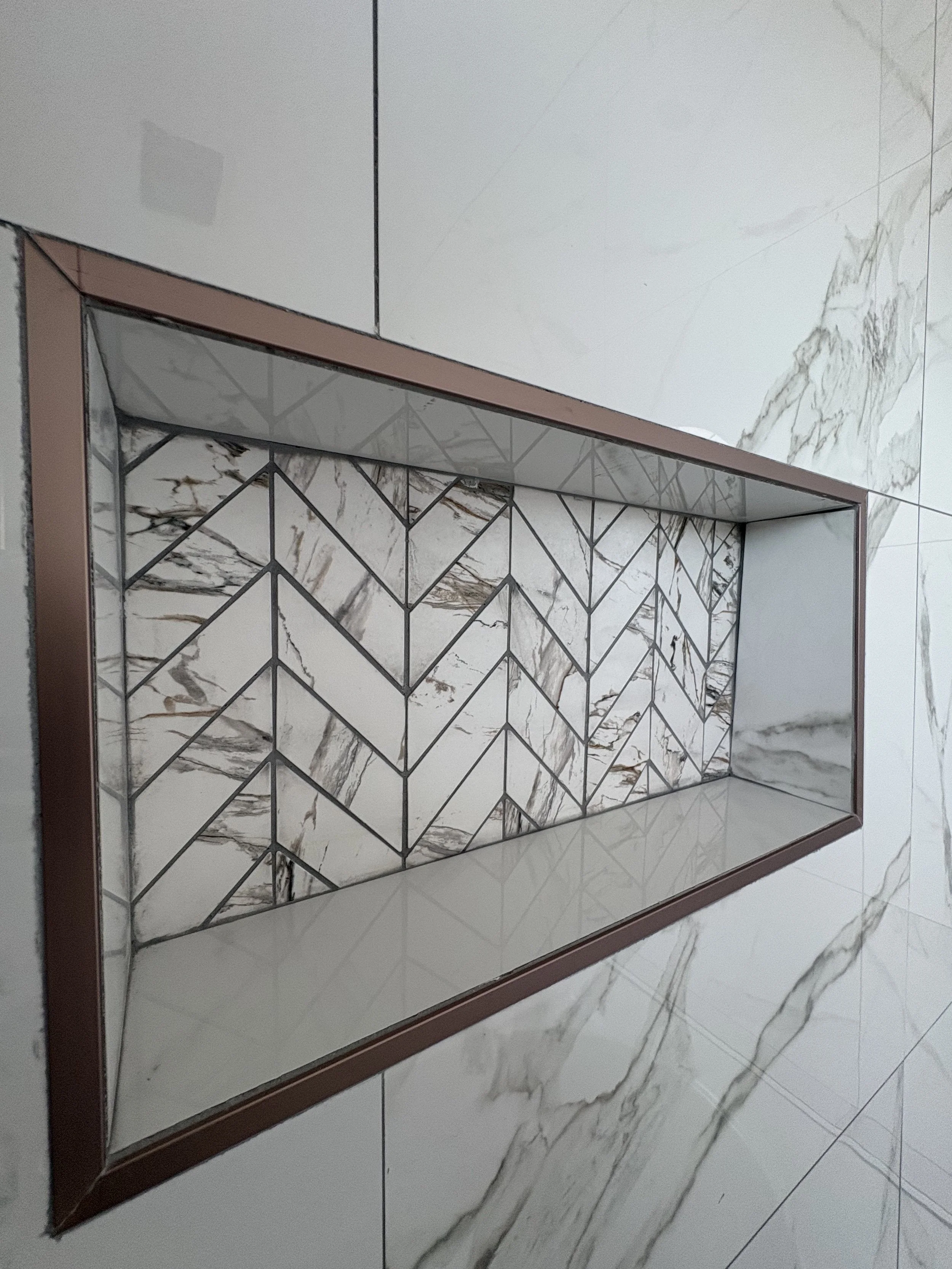 Close-up of a wall mirror with a marble tile border and background, reflecting a marble floor done by Astwood Flooring tiling job