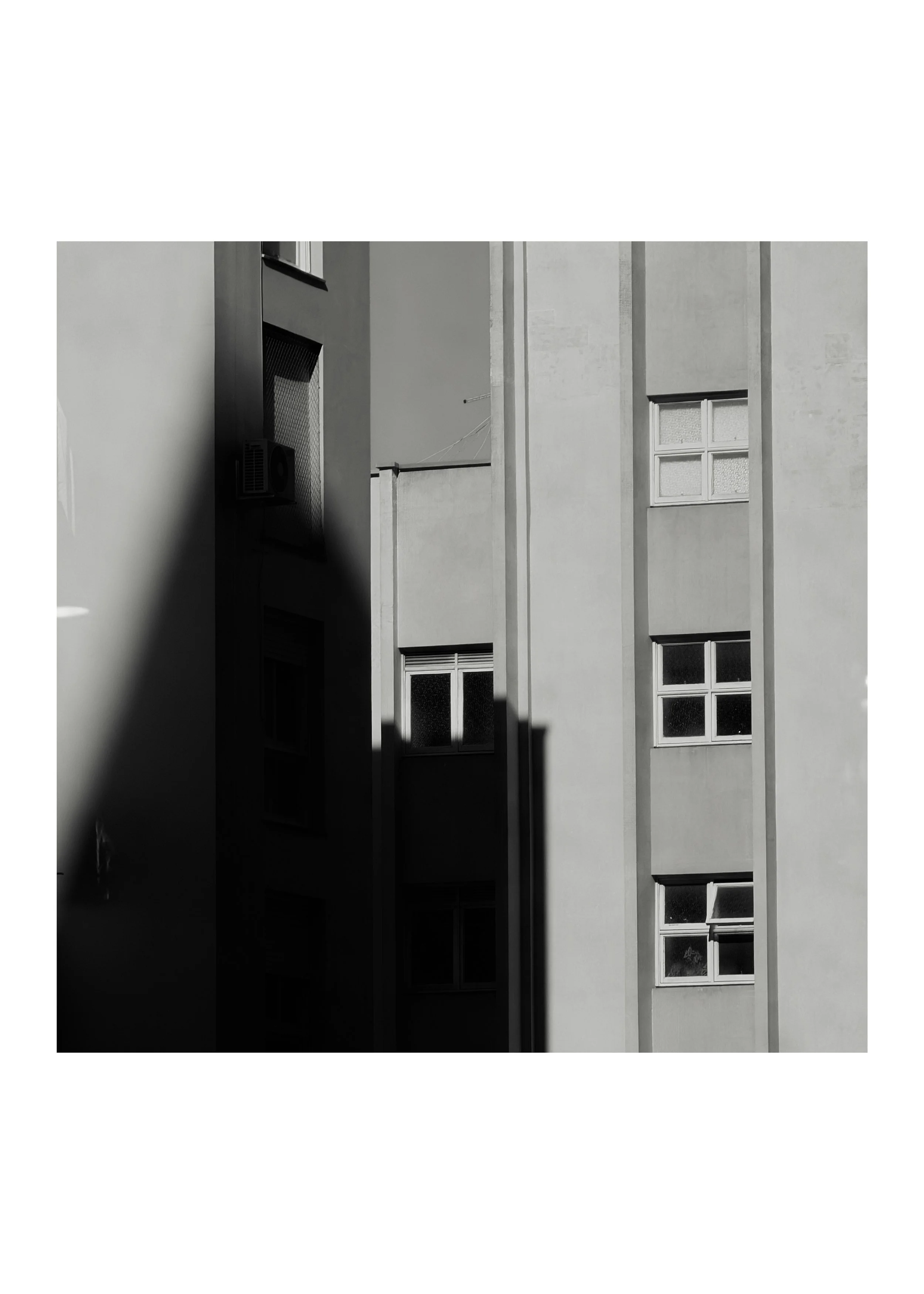 Black and white photo of a modern building's exterior with windows and vertical beams.