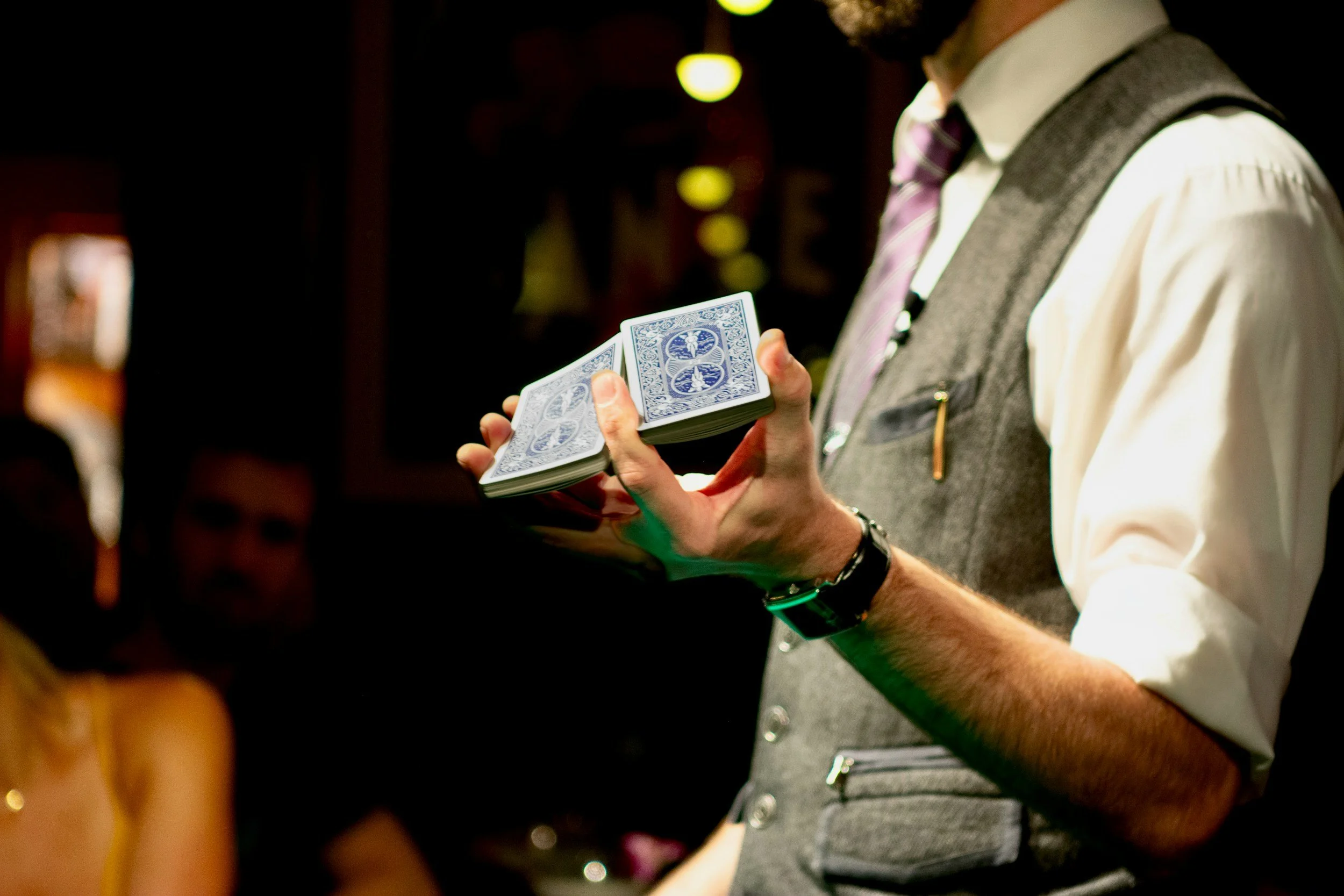 Person holding a deck of playing cards in a dimly lit setting.