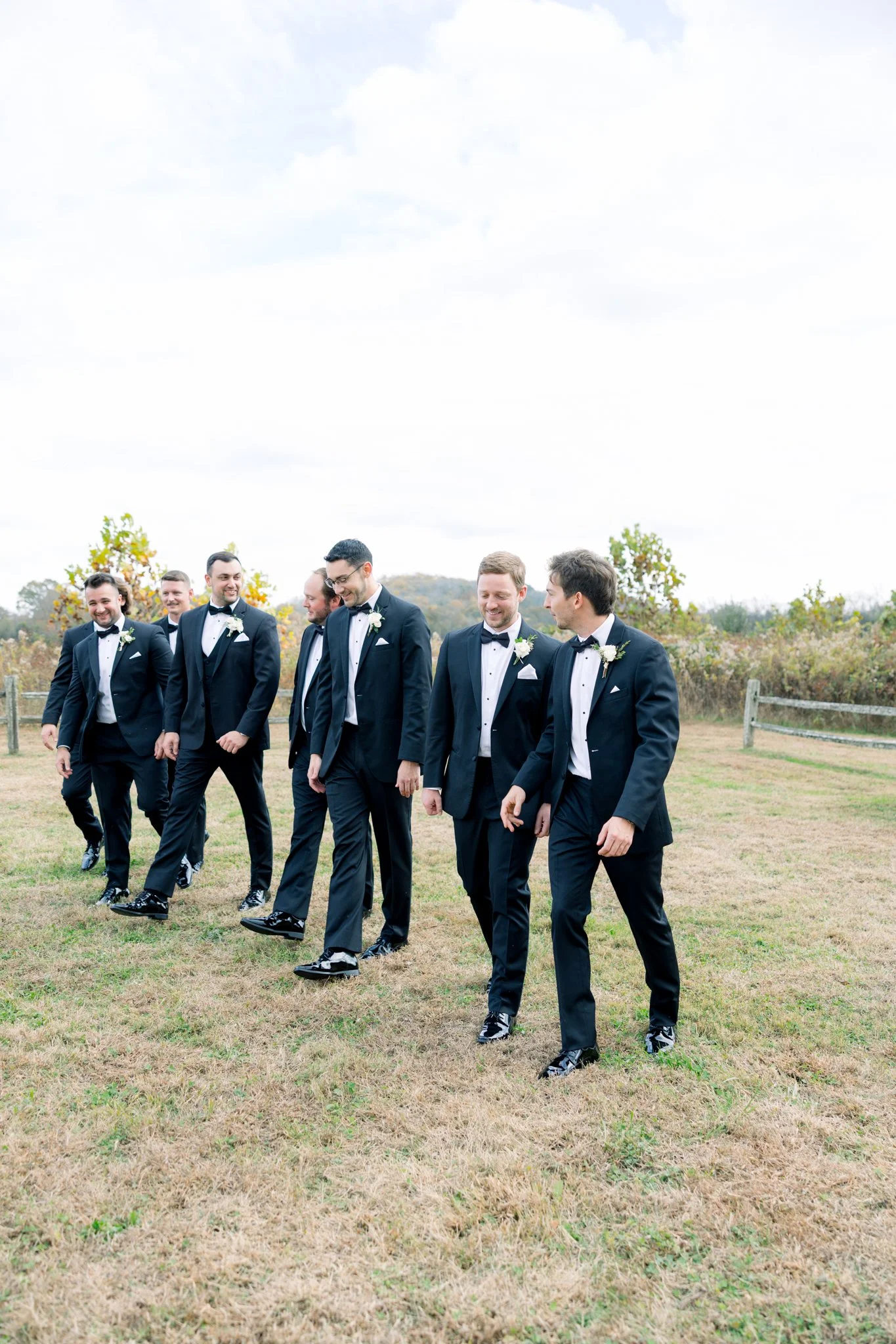 Group of men in tuxedos walking on grass outdoors during daytime