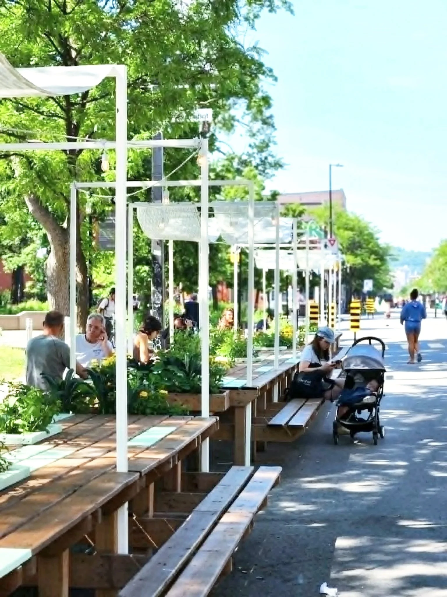 Photo of pedestrianized street with seating, shading, trees and planters.