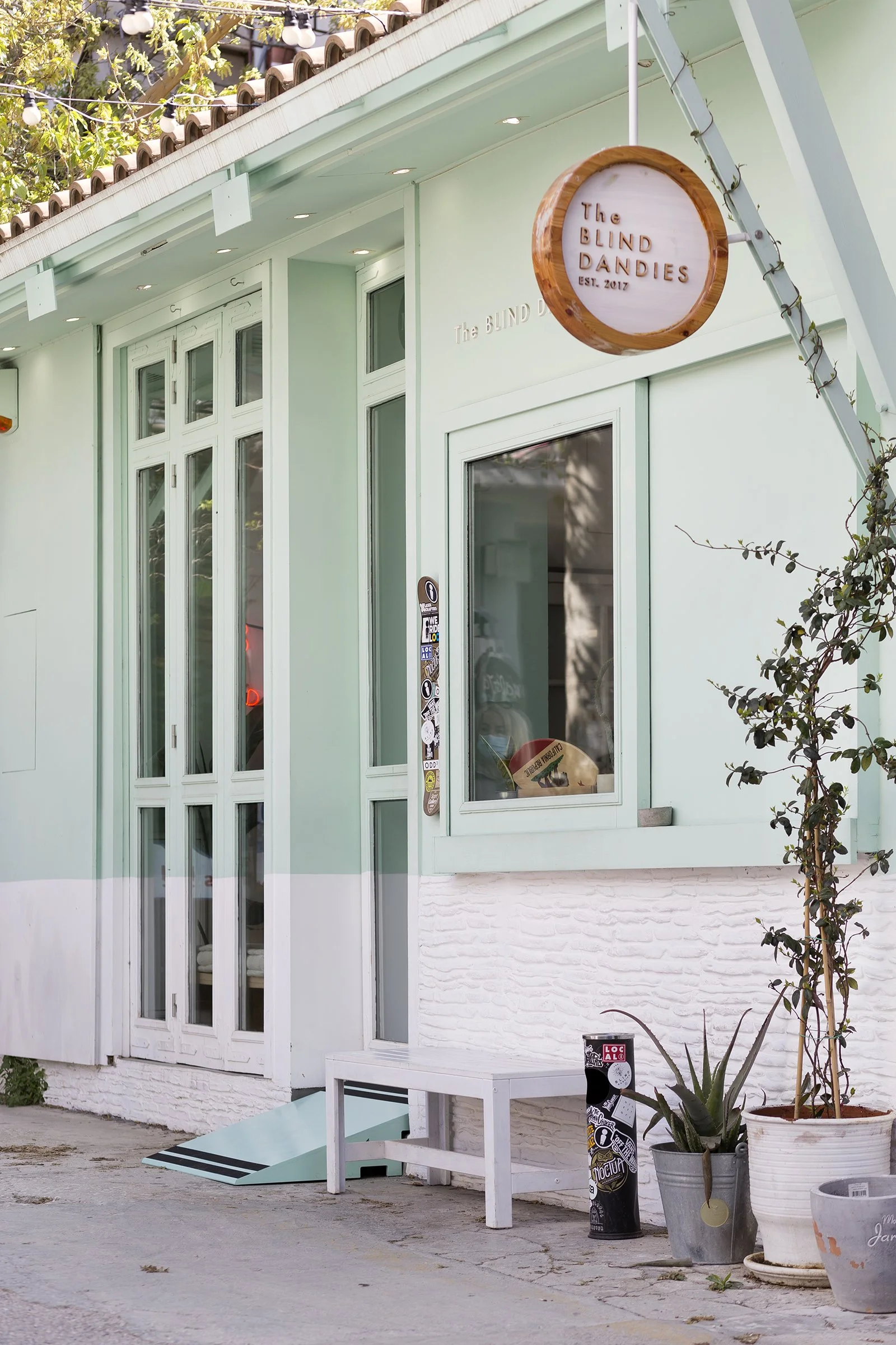 Photo of a local store in Athens showing the implementation of the Ramp It project in collaboration with AccessLab, featuring a light green wooden accessibility ramp structure.