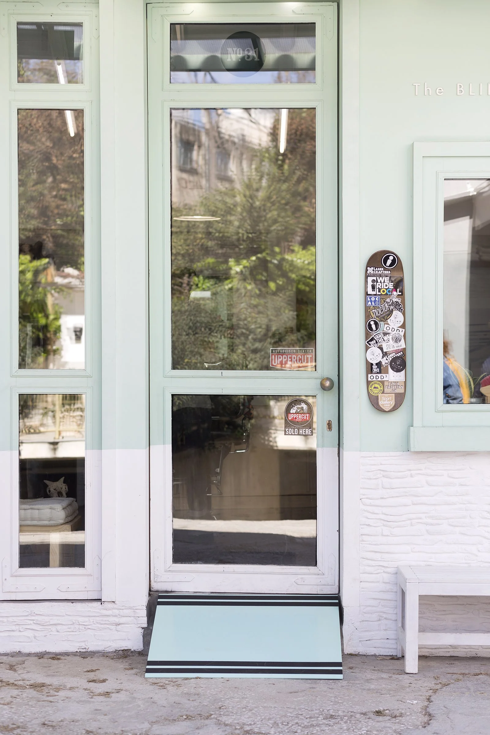 Photo of the main entrance of a local store in Athens showing the Ramp It project in collaboration with AccessLab, featuring a light green wooden ramp improving accessibility.