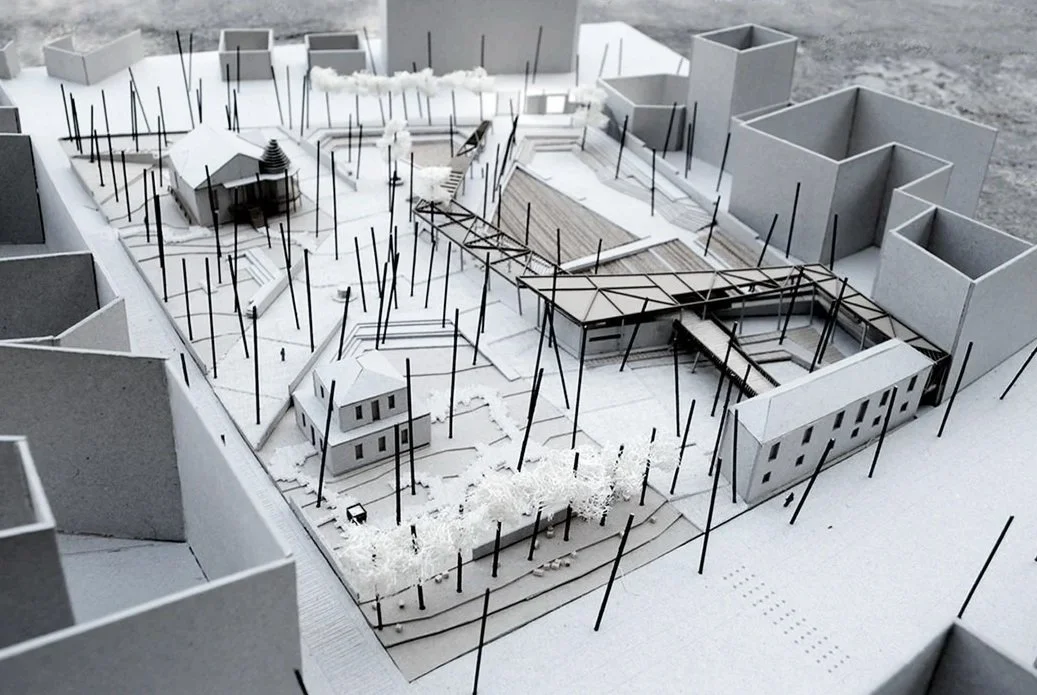 Architectural model of a building complex with trees and pathways, under construction with visible framing.