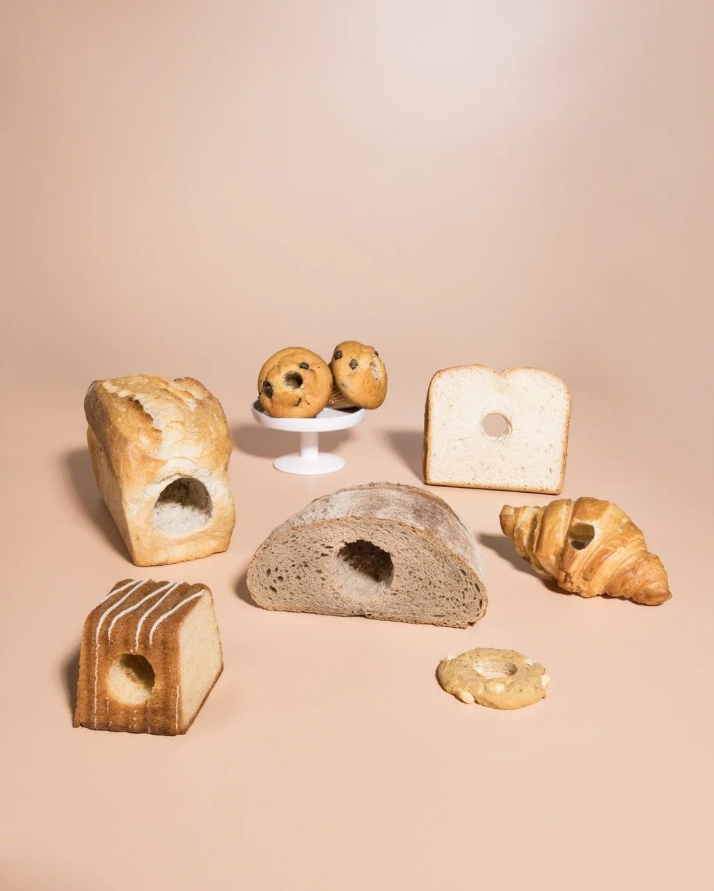 Verschiedene Brotsorten und Kekse auf einer beige Oberfläche, mit einem neutralen Hintergrund.